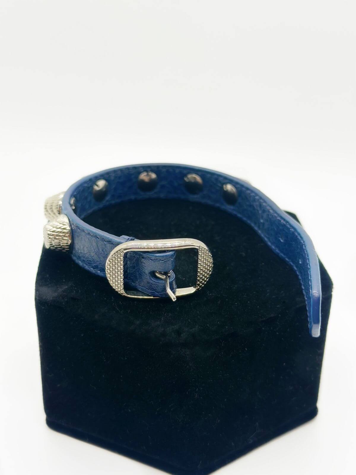 Balenciaga studded leather bracelet on black fixture on white background.