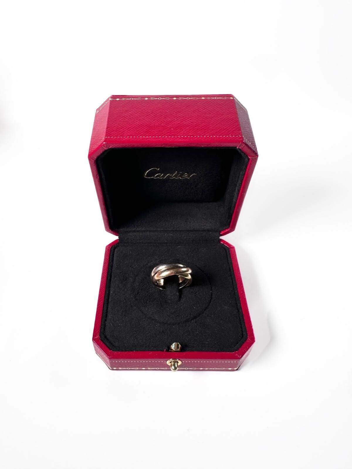 Cartier Gold Trinity ring in a Cartier jewelry box on a white background