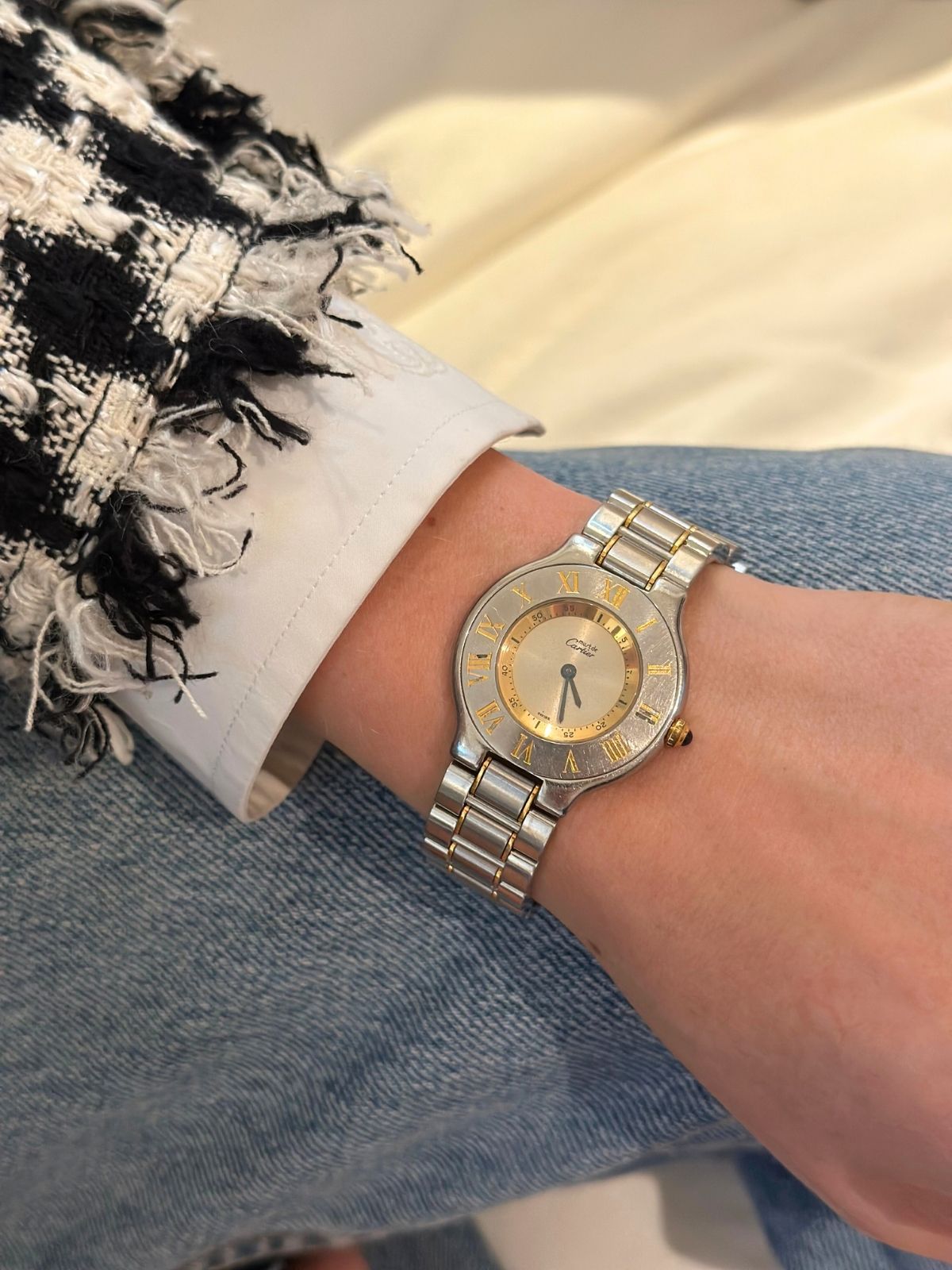 Model wearing Cartier must watch in stainless silver and gold round dial.
