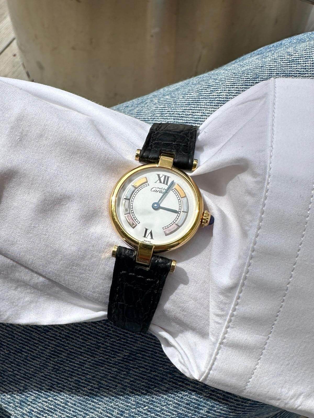 Model wearing Cartier Gold watch with black leather strap on a white fabric background