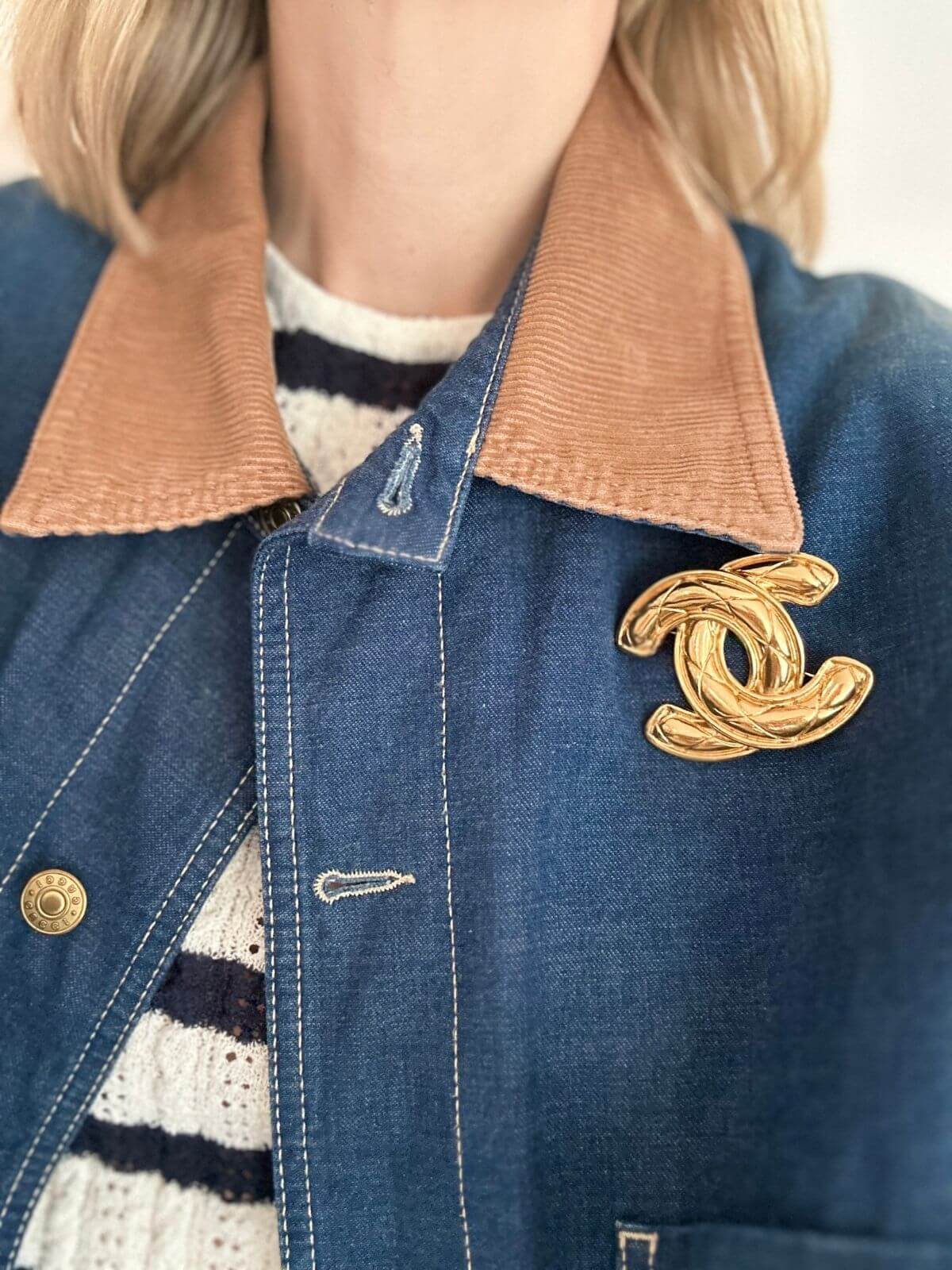 Gold Chanel brooch on model with jean jacket