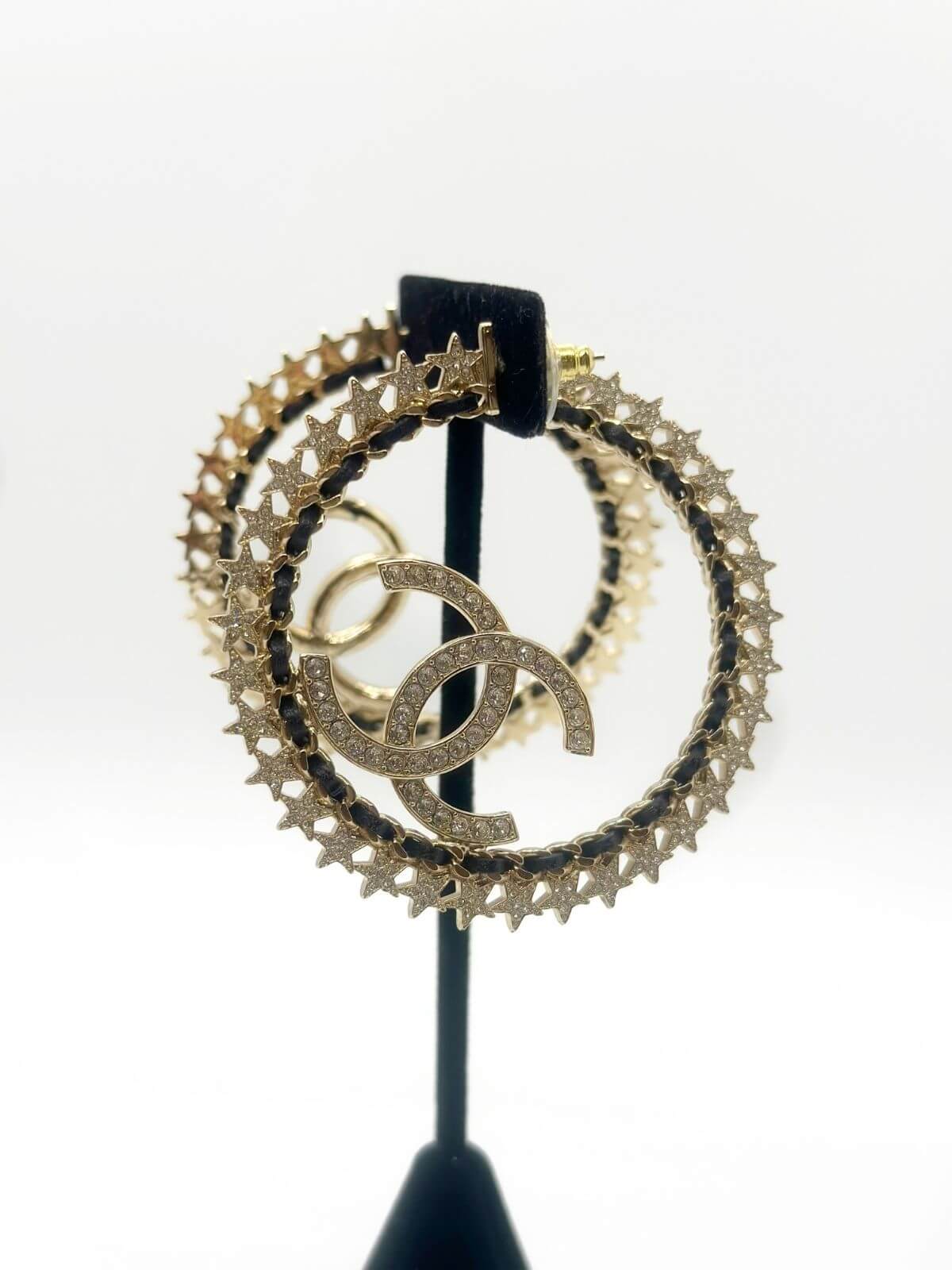 Chanel star hoop earring on fixture on white background.