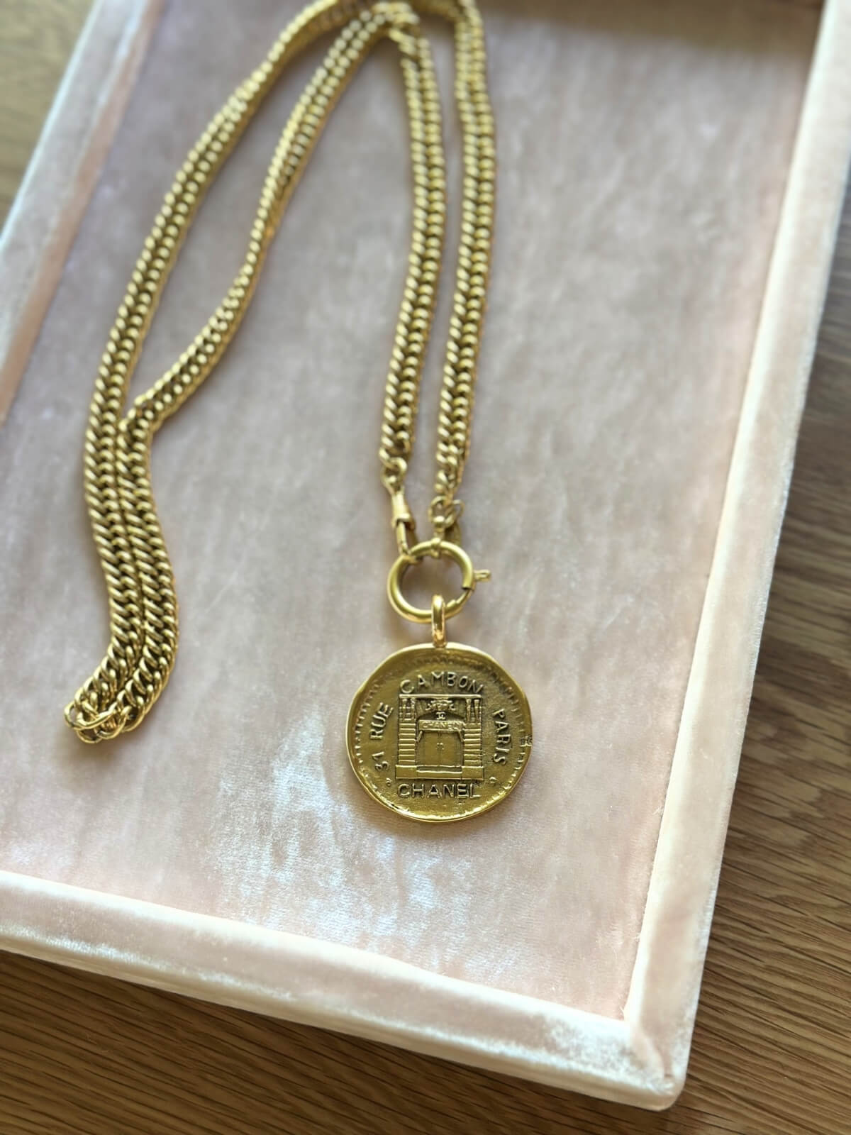 Louise Row Studio featuring vintage Chanel rue de Cambon gold necklace with long chain and medallion on a pink display tray.