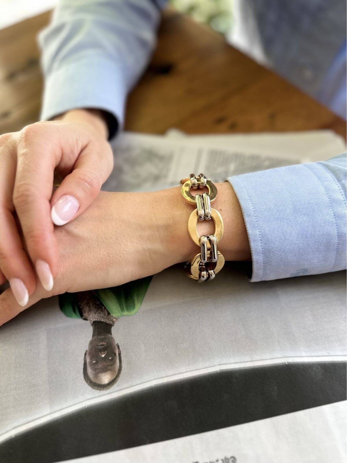 Gold chain bracelet on a wrist with a blurred background
