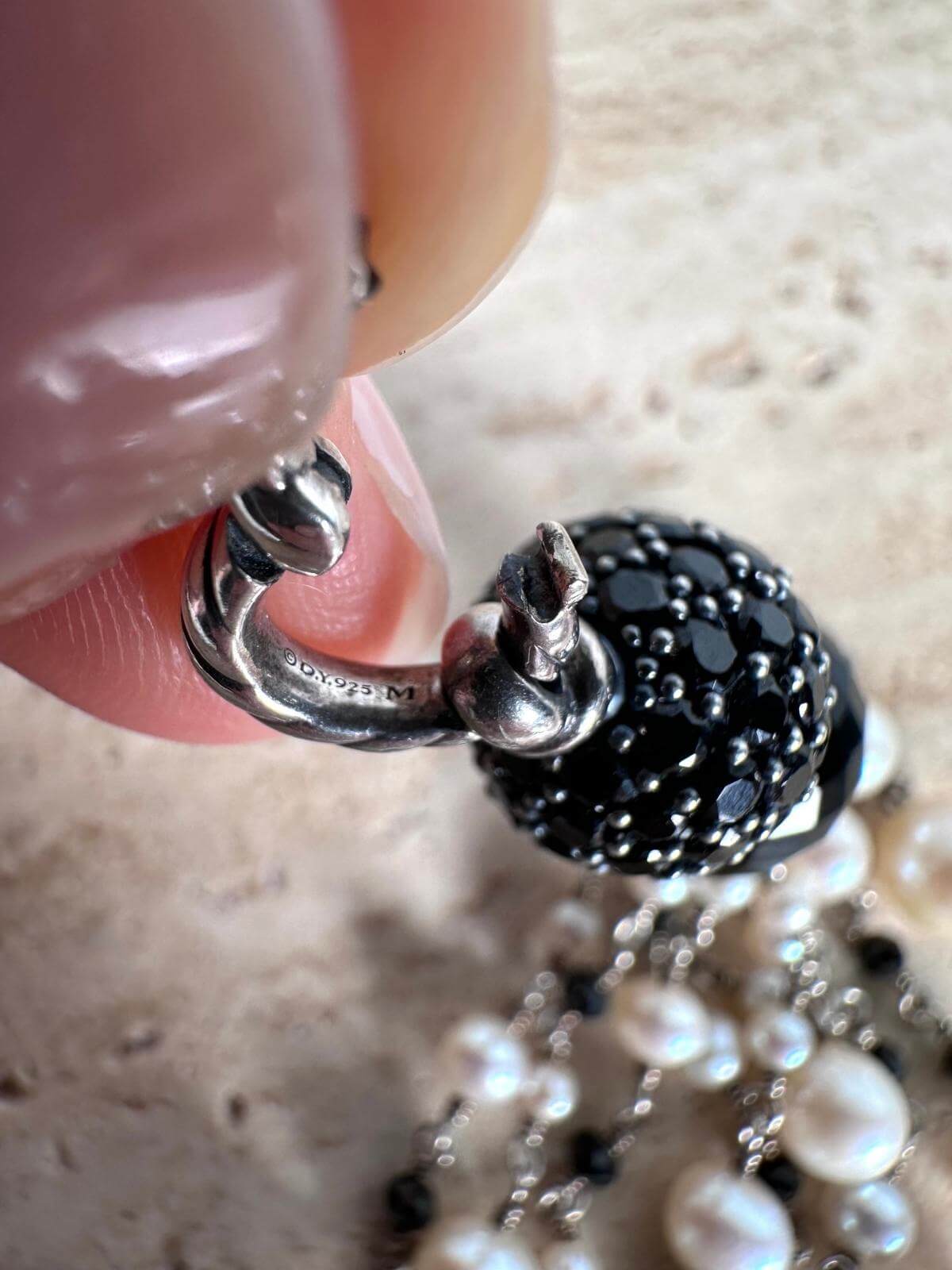 Hand holding pendant, Close up of signature on clasp of pendant, DY stamp