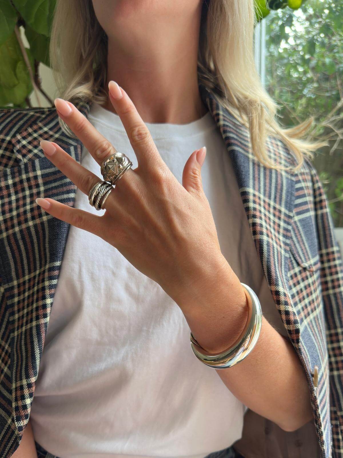 Model wearing 2 rings but showing DY renaissance ring with a hand open in blazer on chair