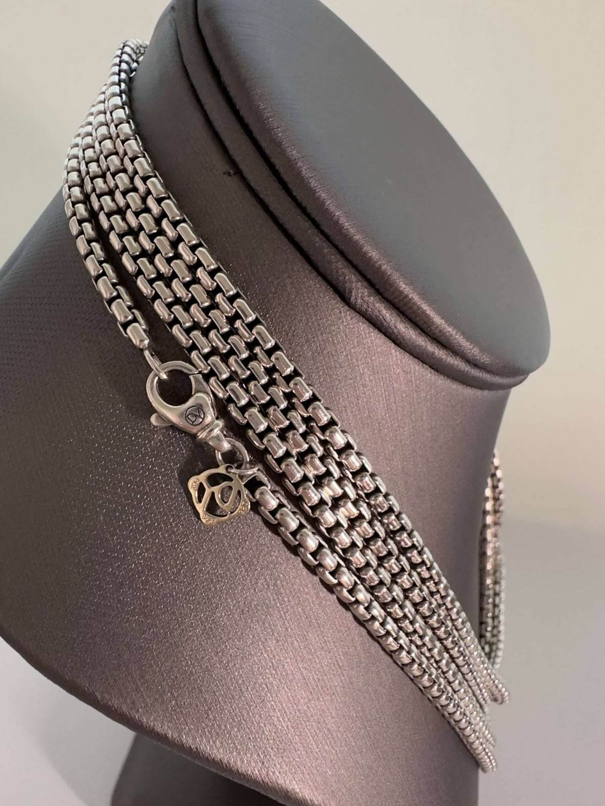 Close up of silver chain necklace showing clasp with DY logo