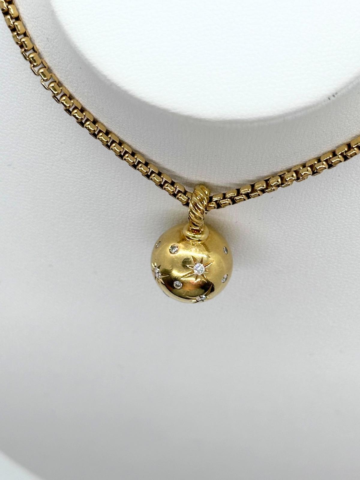 Gold necklace with a spherical pendant on a white background