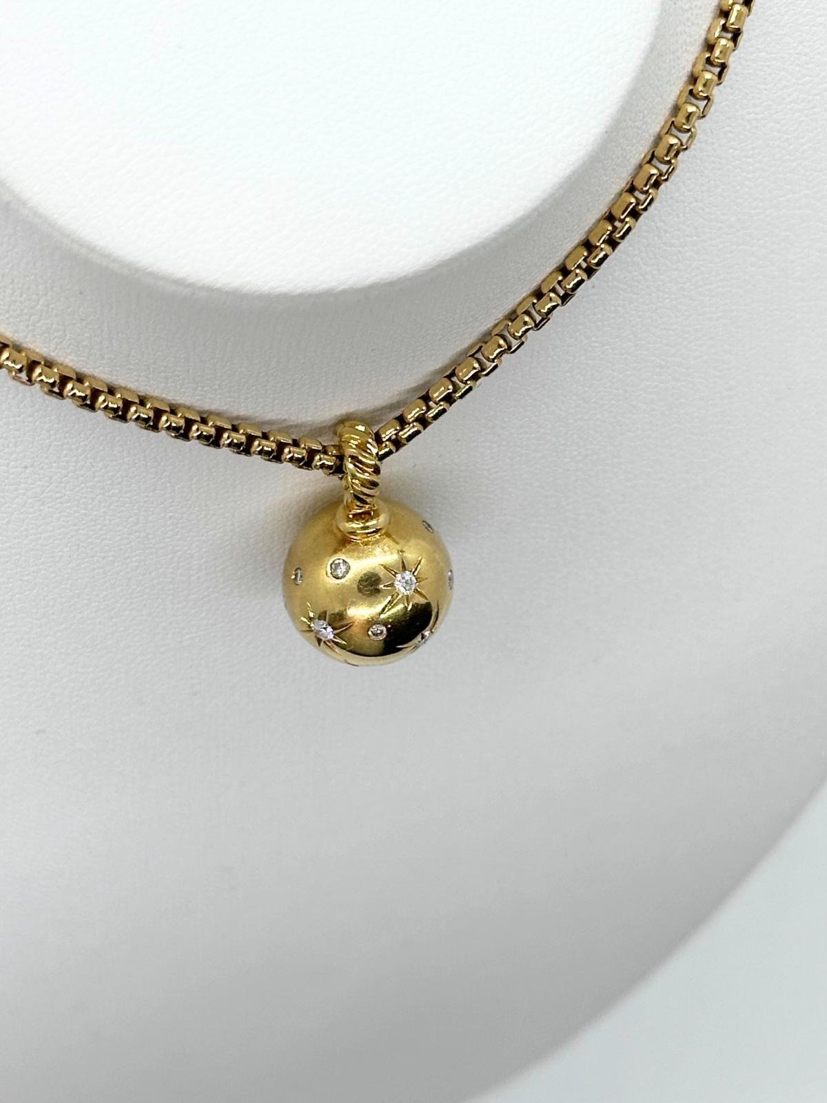 Gold necklace with a spherical pendant on a white background
