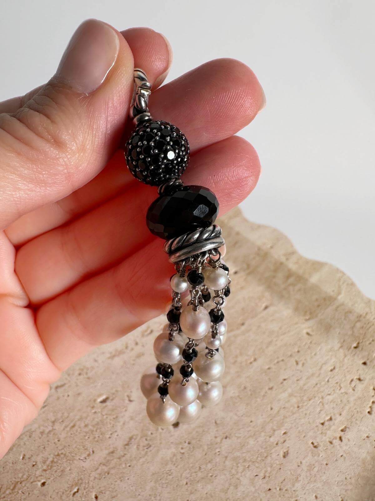 hand holding close up of Pearl beads and onyx pendant set in silver on marble background