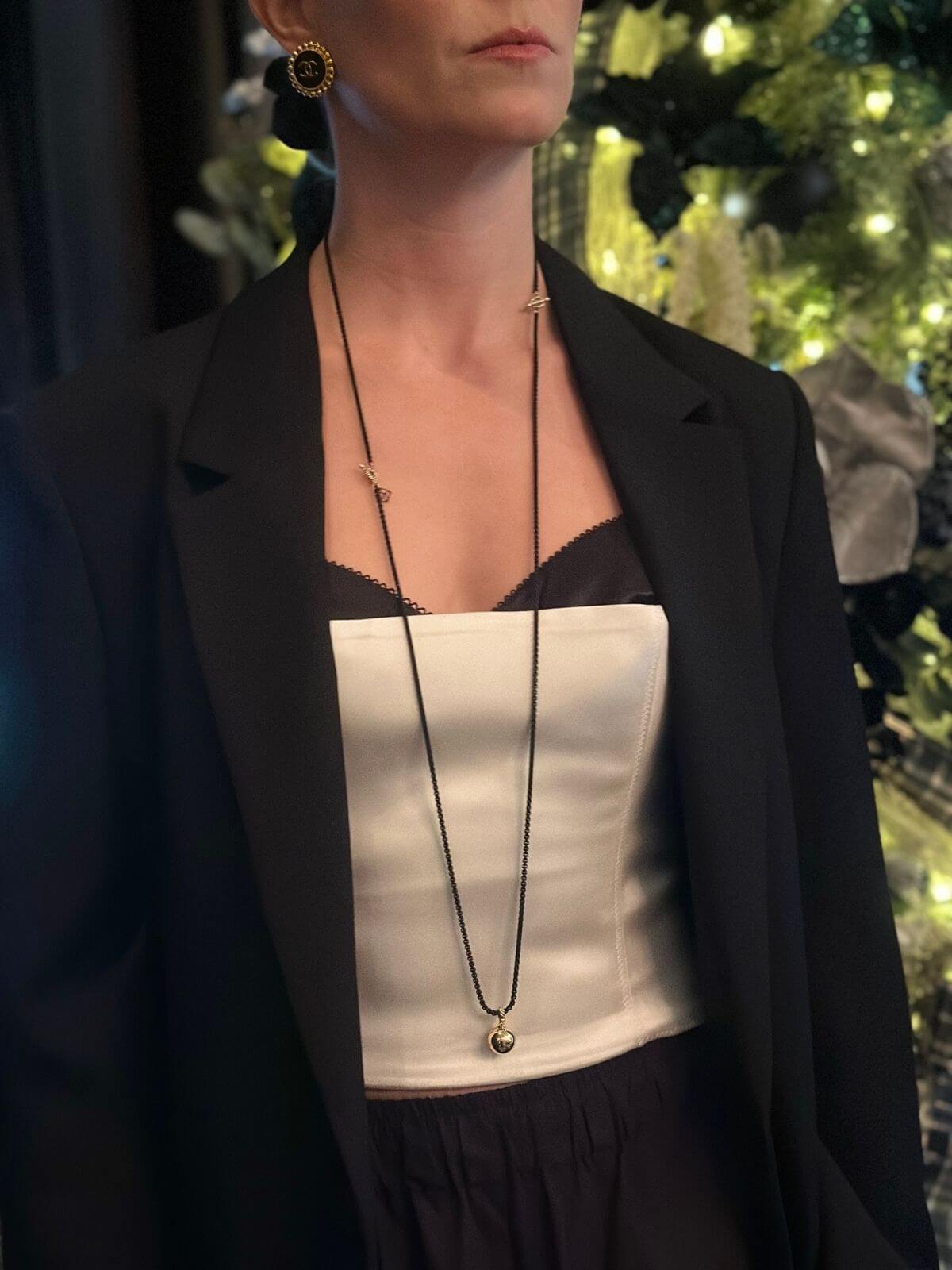 Person wearing a black blazer over a white top with a blurred festive background