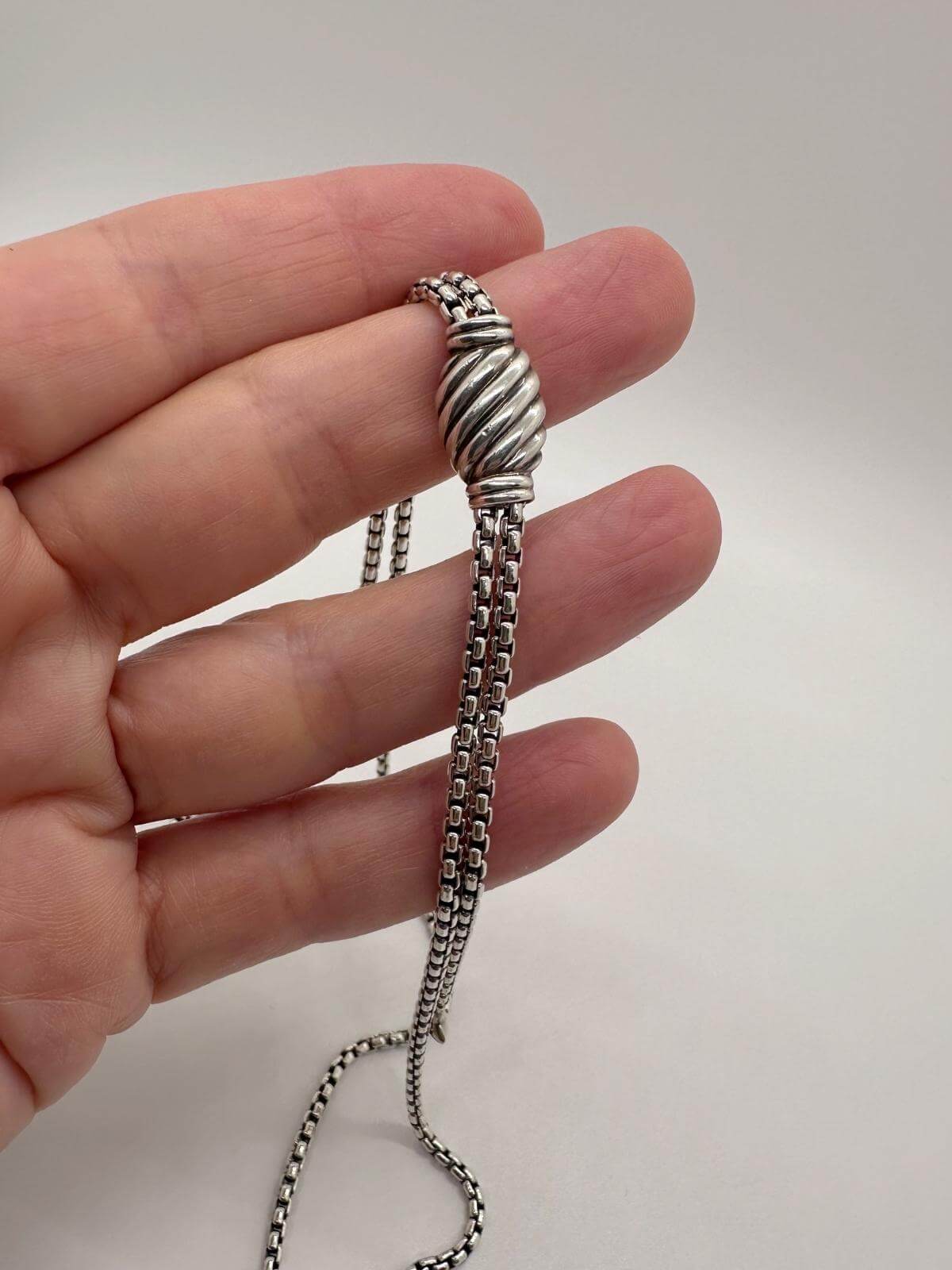 Detail of clasp of DY box chain necklace held by hand