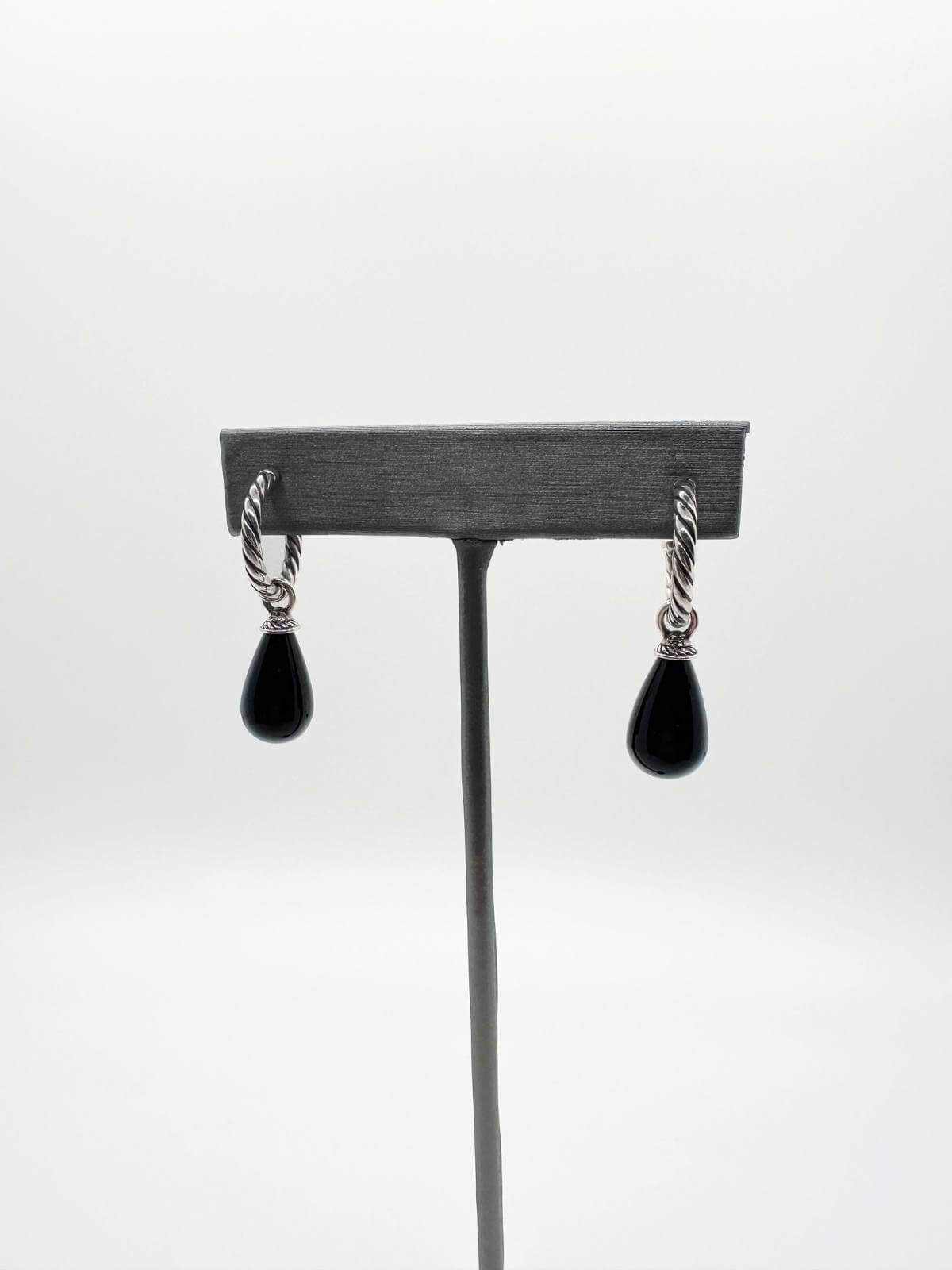 David Yurman Pair of earrings with black teardrop pendants on a gray stand against a white background