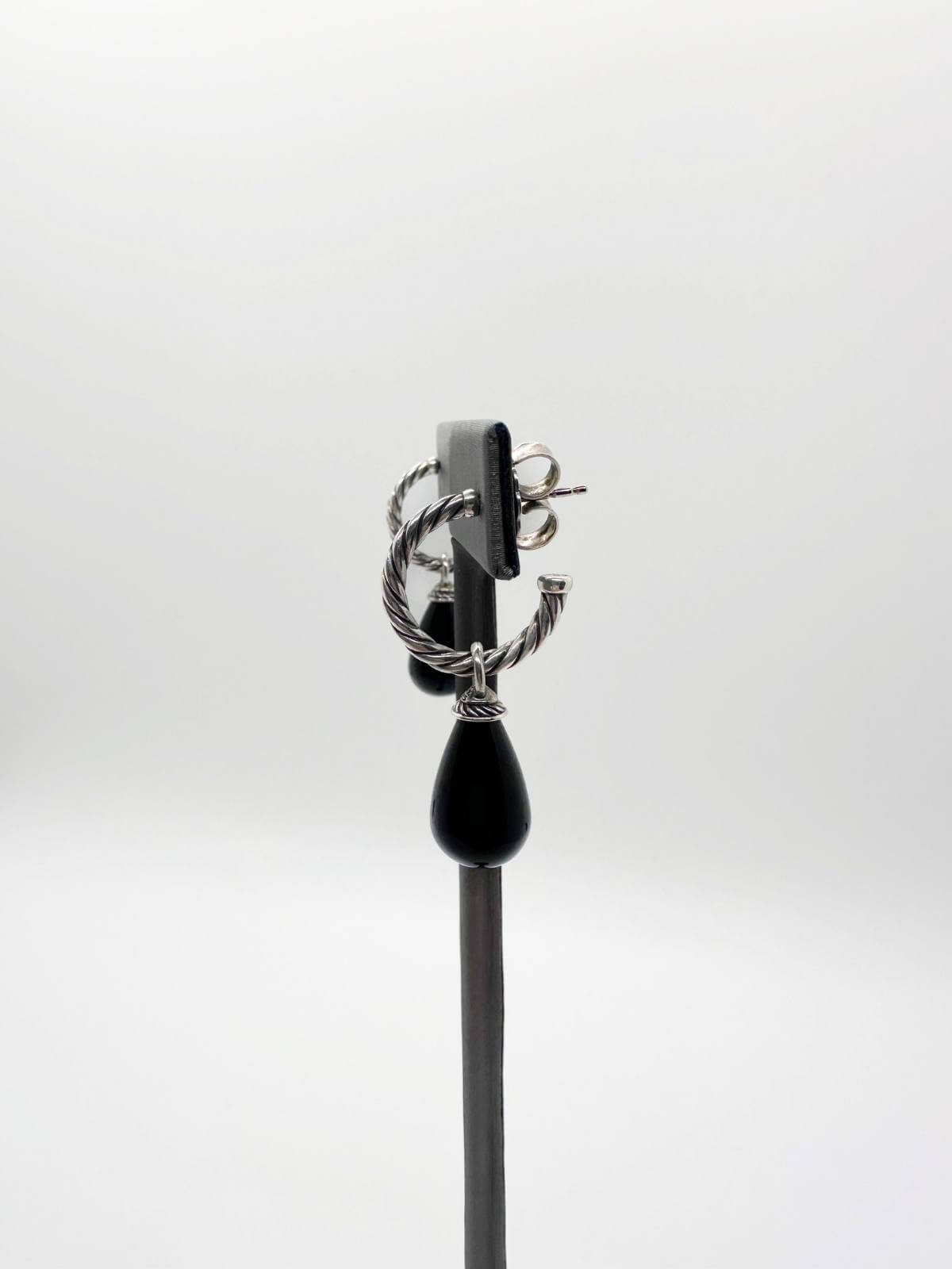 David Yurman Pair of earrings with black teardrop pendants on a gray stand against a white background