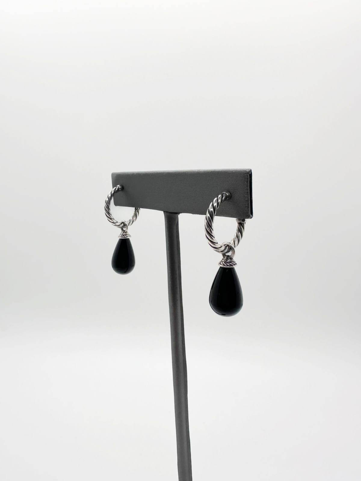 David Yurman Pair of earrings with black teardrop pendants on a gray stand against a white background