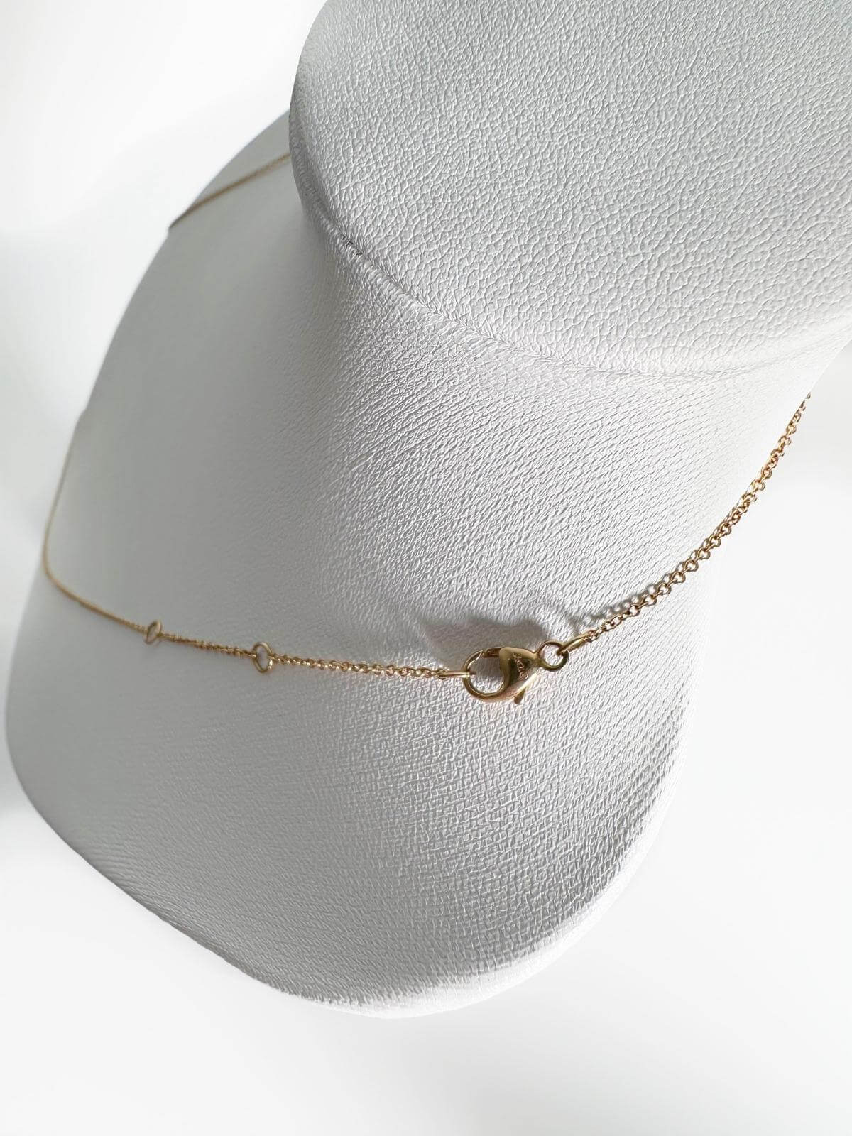 Clasp showing signature of DY Gold necklace on a grey mannequin bust against a white background