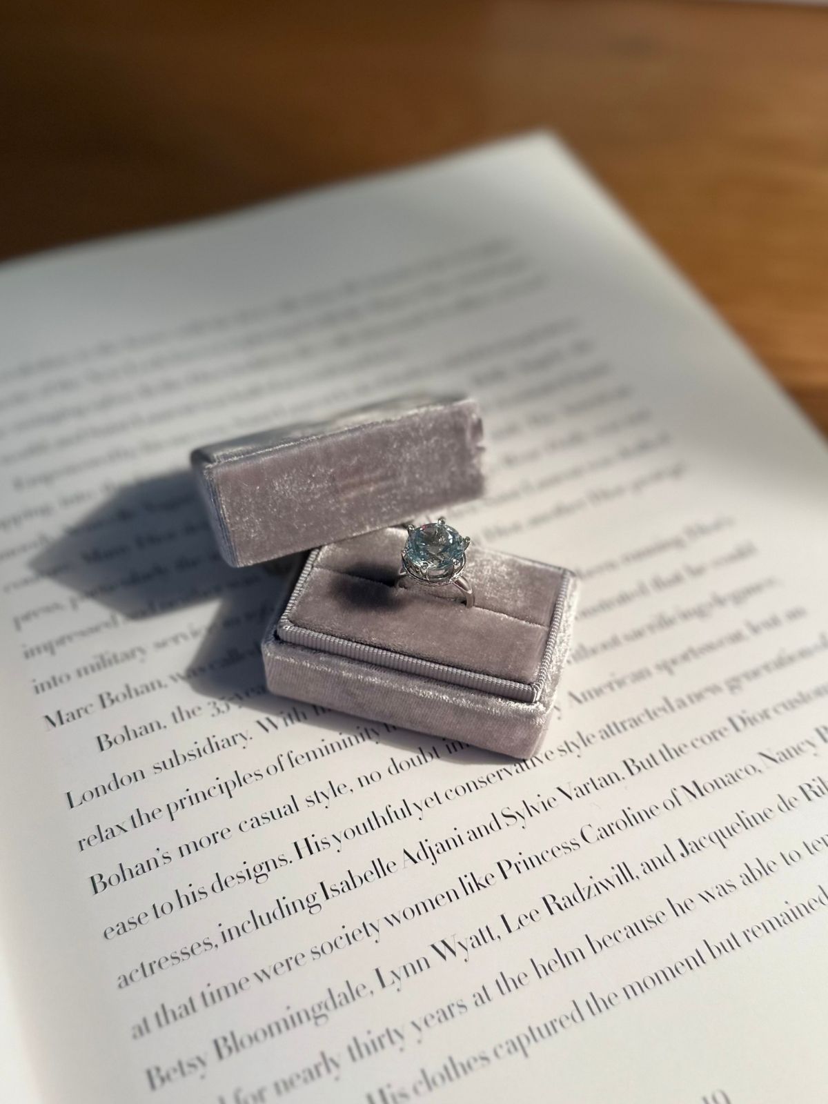 Silver ring box with a aquamarine ring on an open book