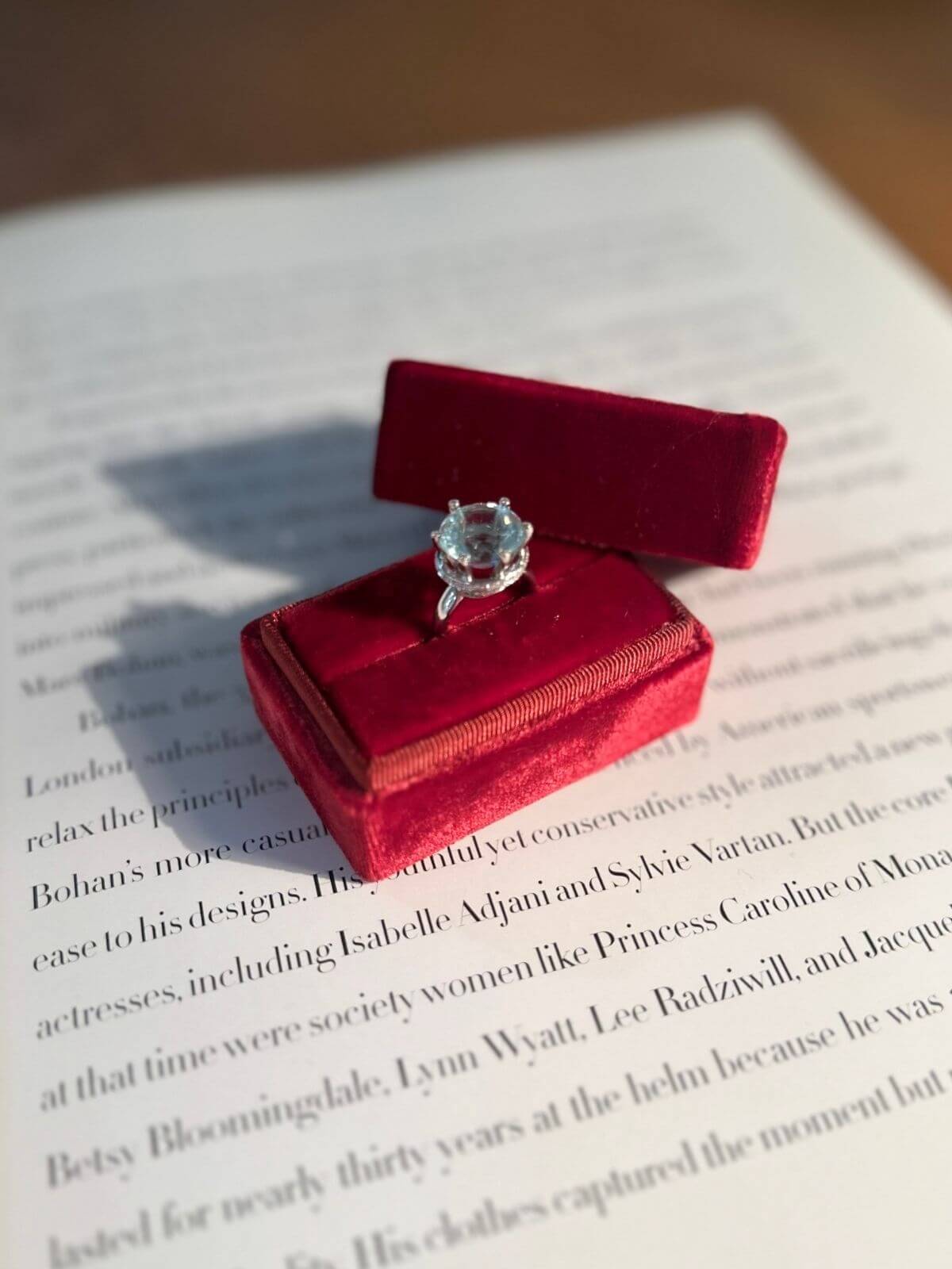 Silver ring box with a aquamarine ring on an open book