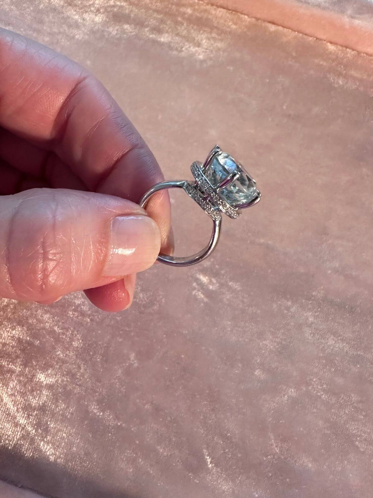Hand holding a diamond ring against a blurred background