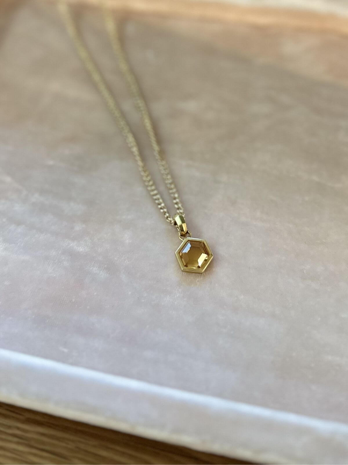 David Yurman Gold necklace with a hexagonal pendant on a pink fixture