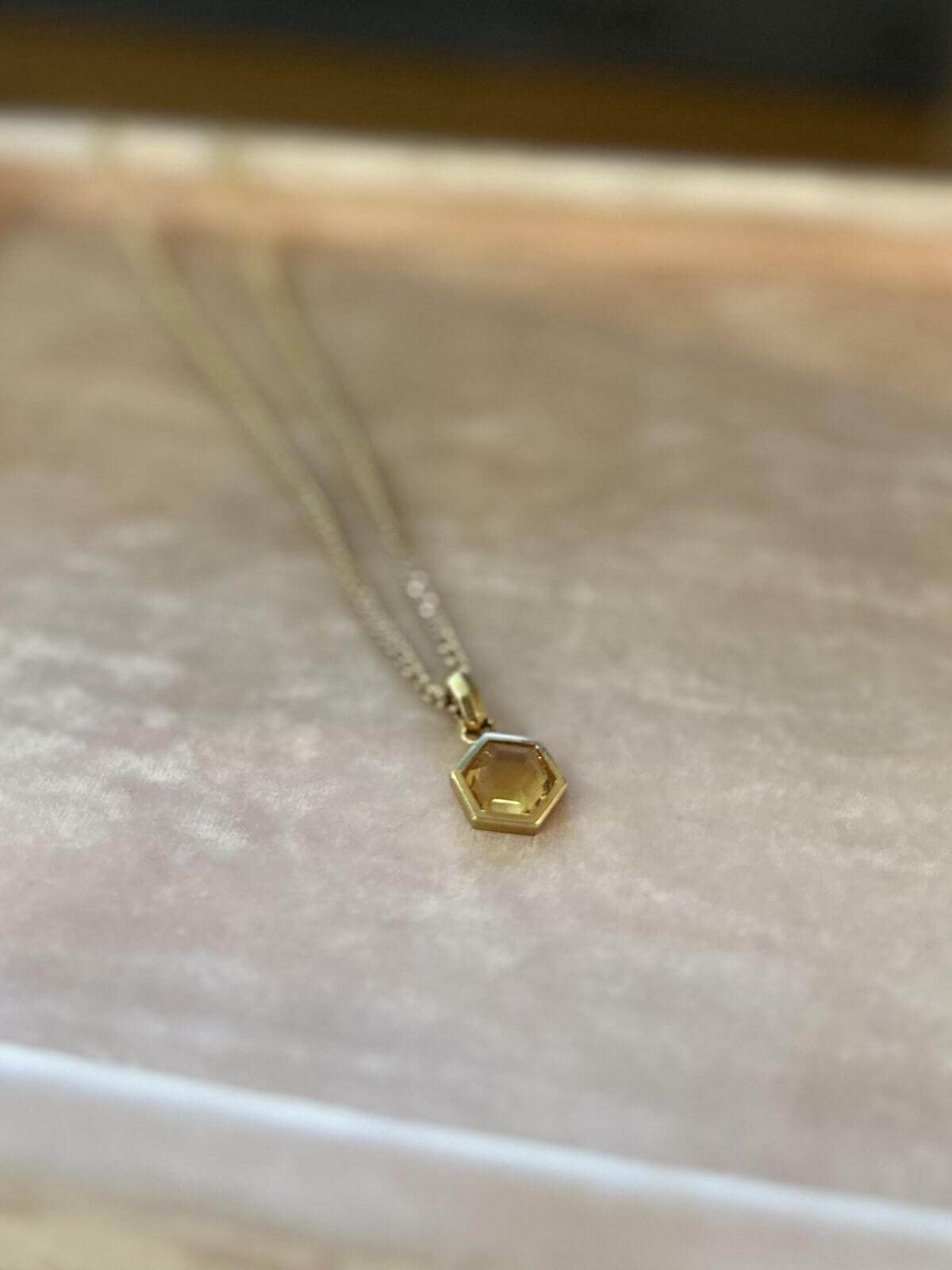 David Yurman Gold necklace with a hexagonal pendant on a pink fixture