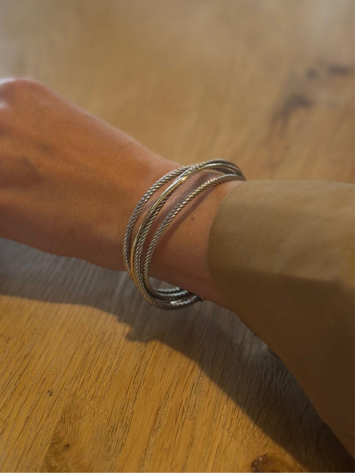 Model arm wearing David Yurman 3 row cuff on wood table
