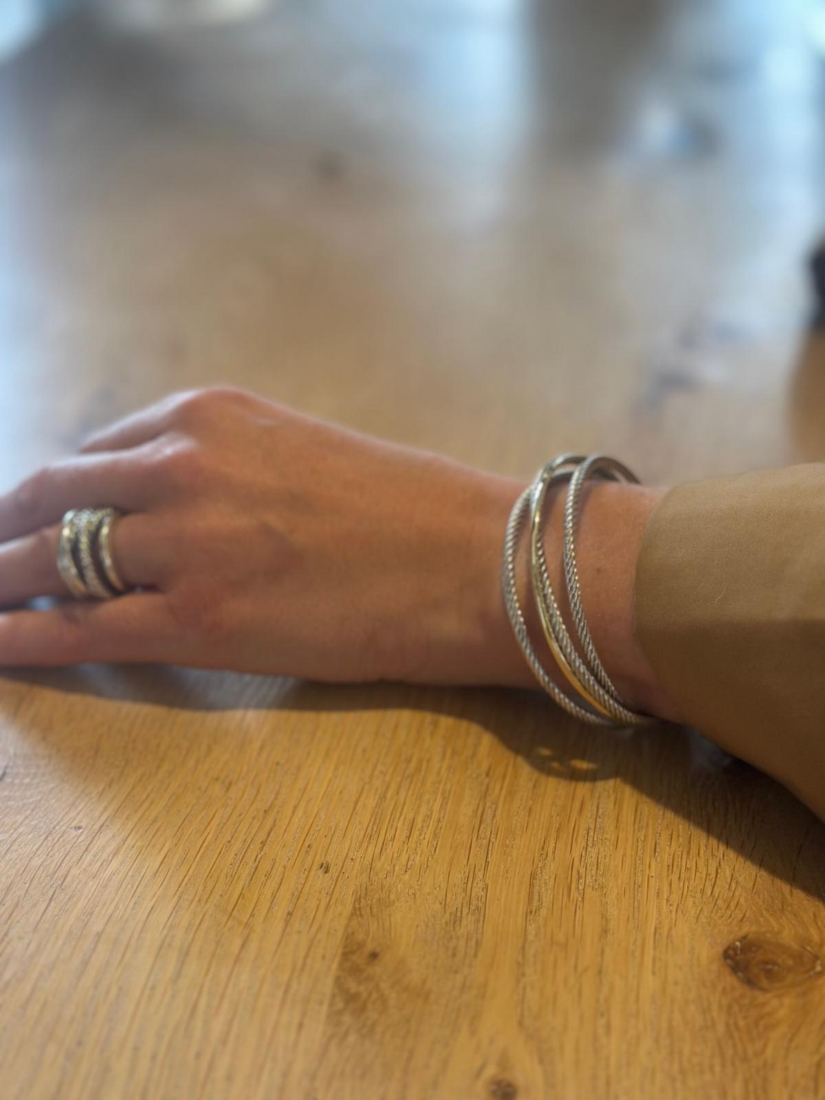 Model arm wearing David Yurman 3 row cuff on wood table