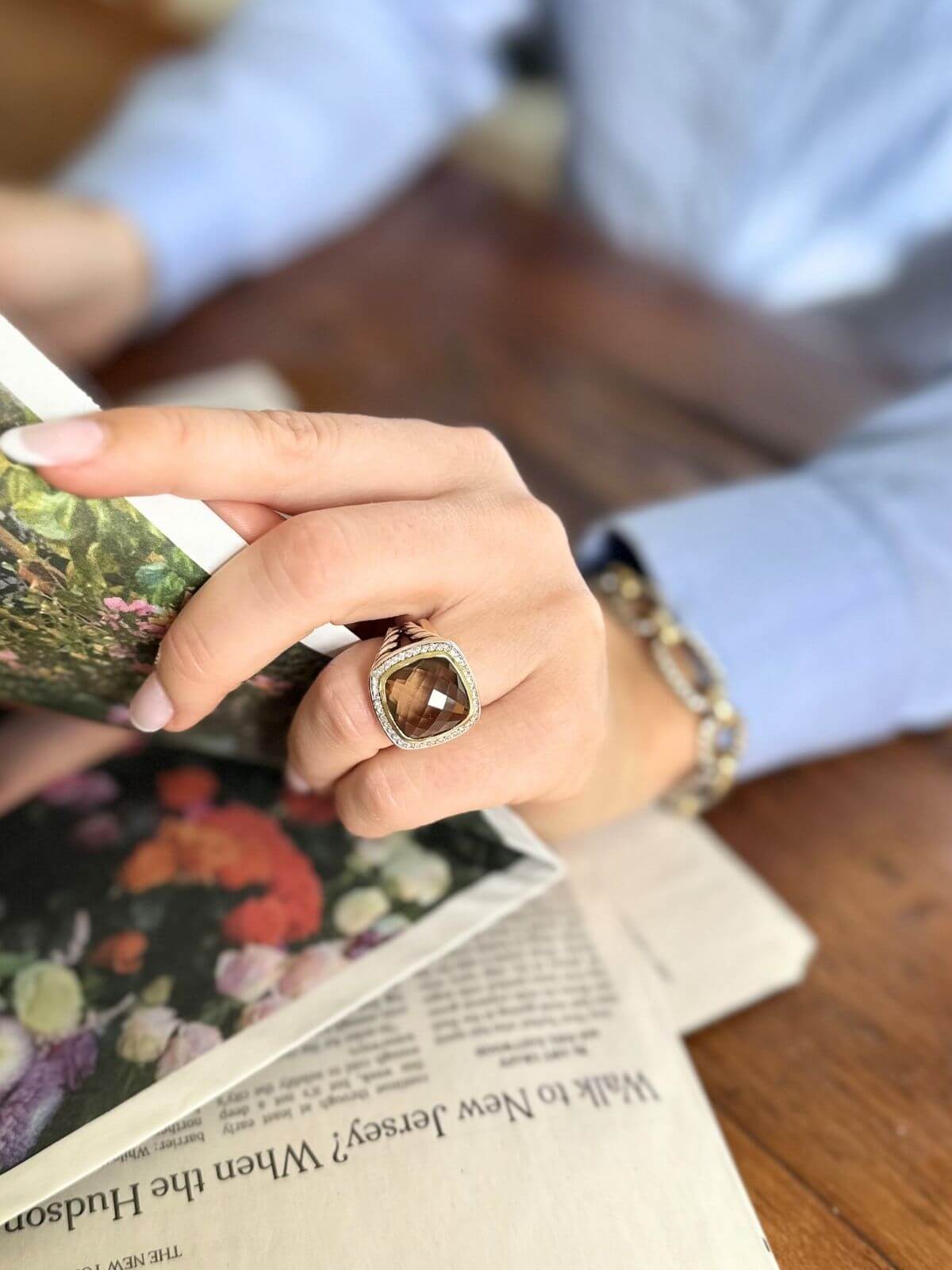 Hand holding a book with a ring on a wooden surface