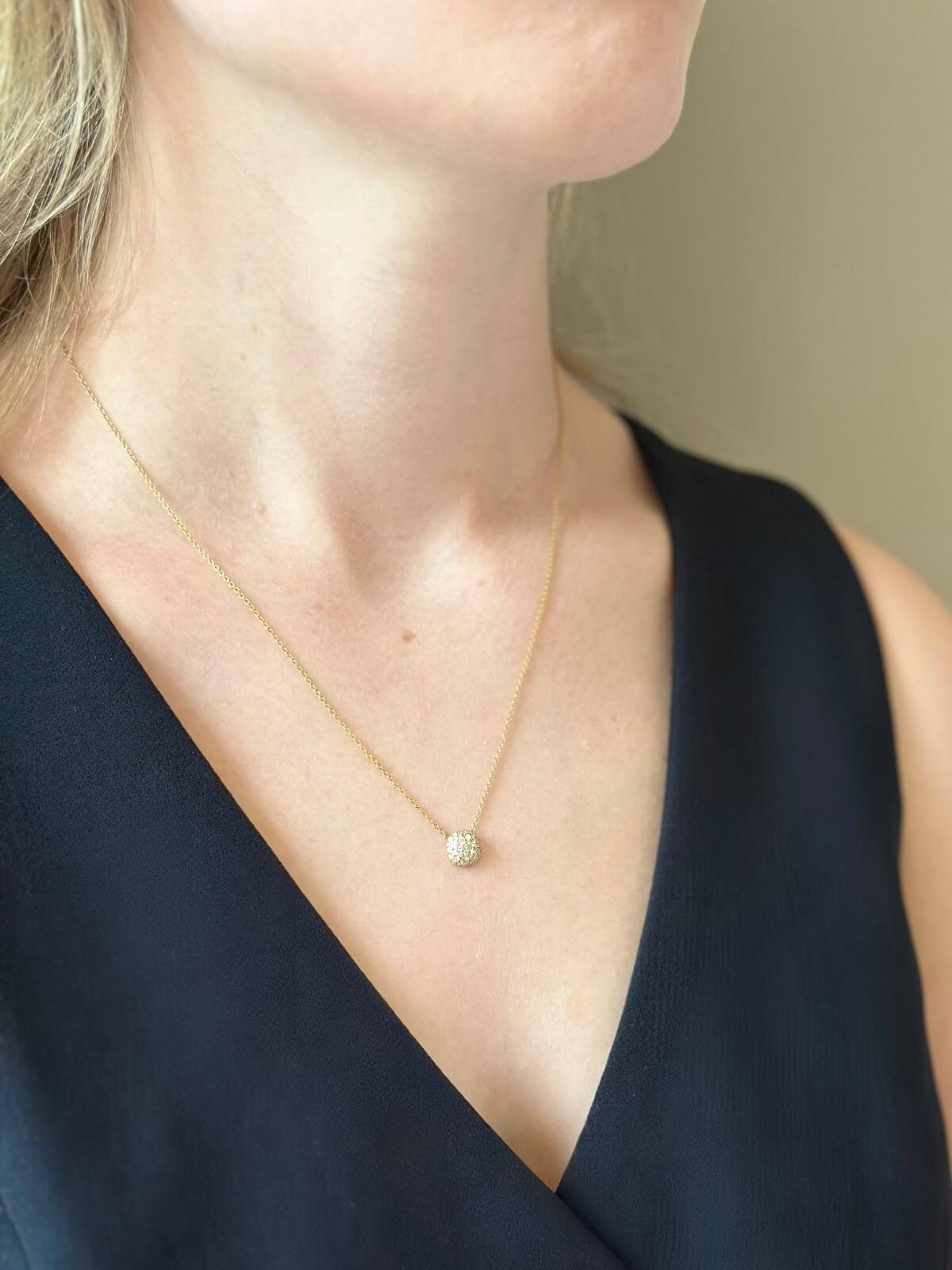 Close up of model wearing DY cushion gold and diamond necklace in a black vest.