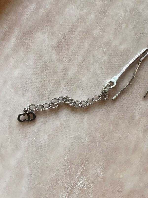 Louise Row Studio featuring Dior silver feather inspired bracelet made of silver and crystals showing detail of CD charm on the end of bracelet.