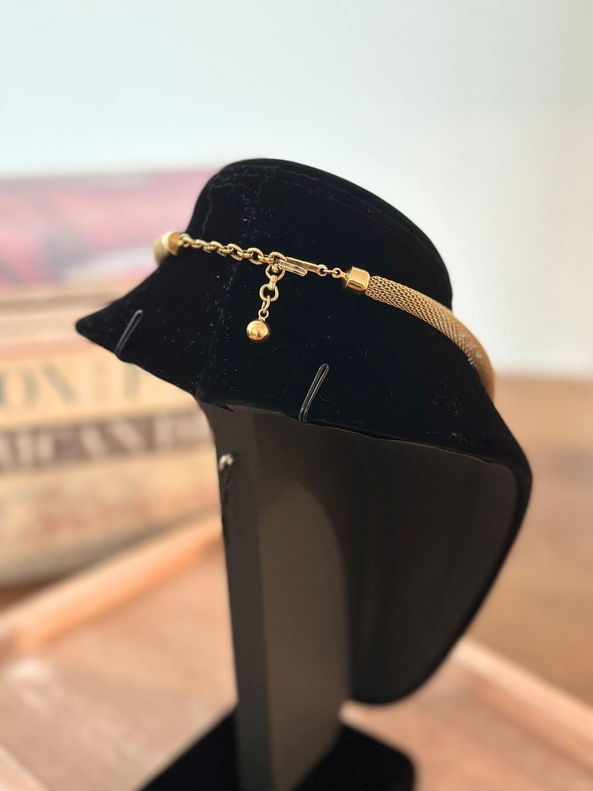 Louise Row Studio Vintage Givenchy necklace of gold 2 tone bow design on black neck form showing the clasp on the back side.
