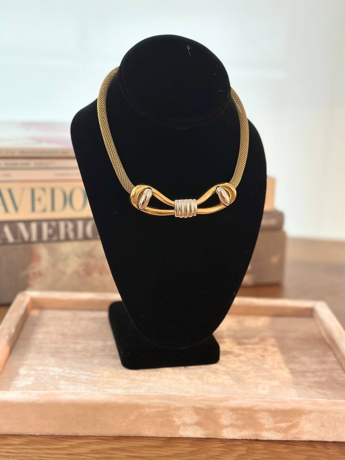 Louise Row Studio Vintage Givenchy necklace of gold 2 tone bow design on black neck form.