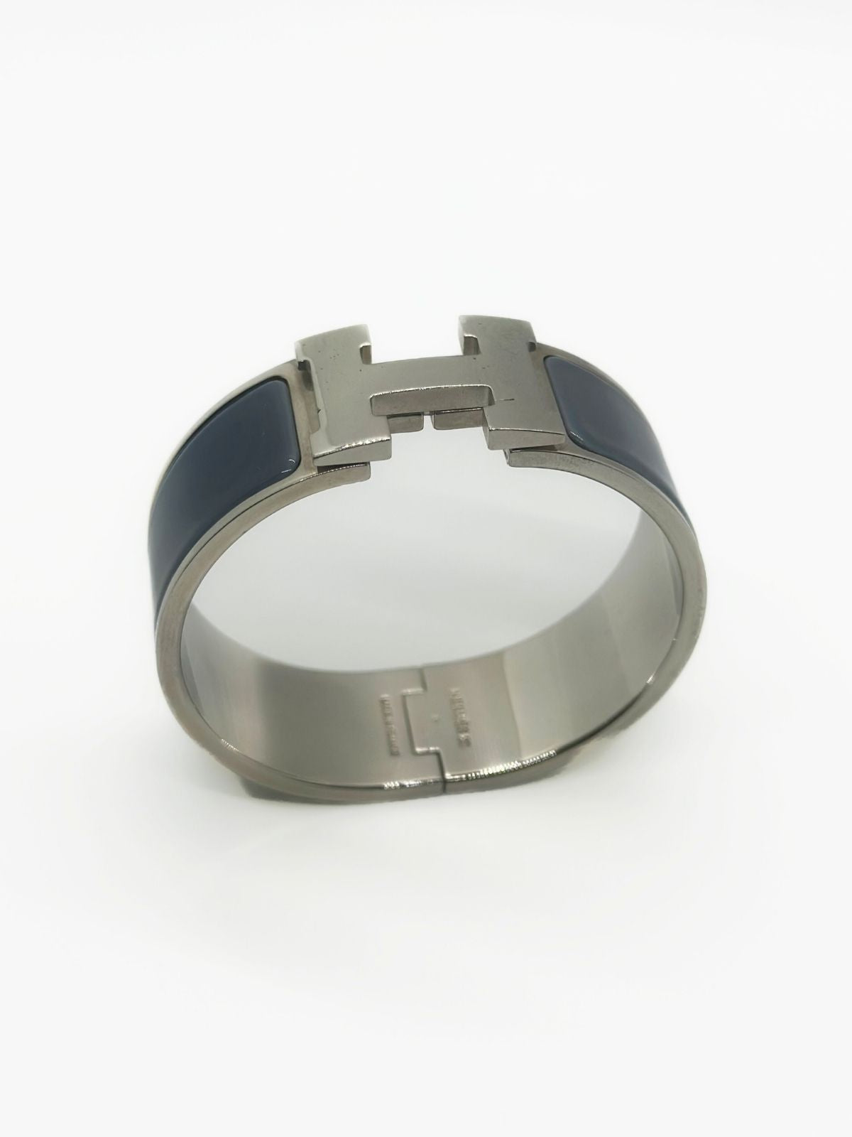 Hermes Clic H Bracelet in stainless steel and enamel on white background. Grey enamel with H in center.