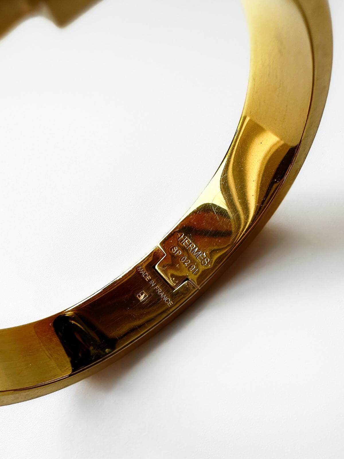 Detail of signature of Hermes Clic H Bracelet with box on marble tray