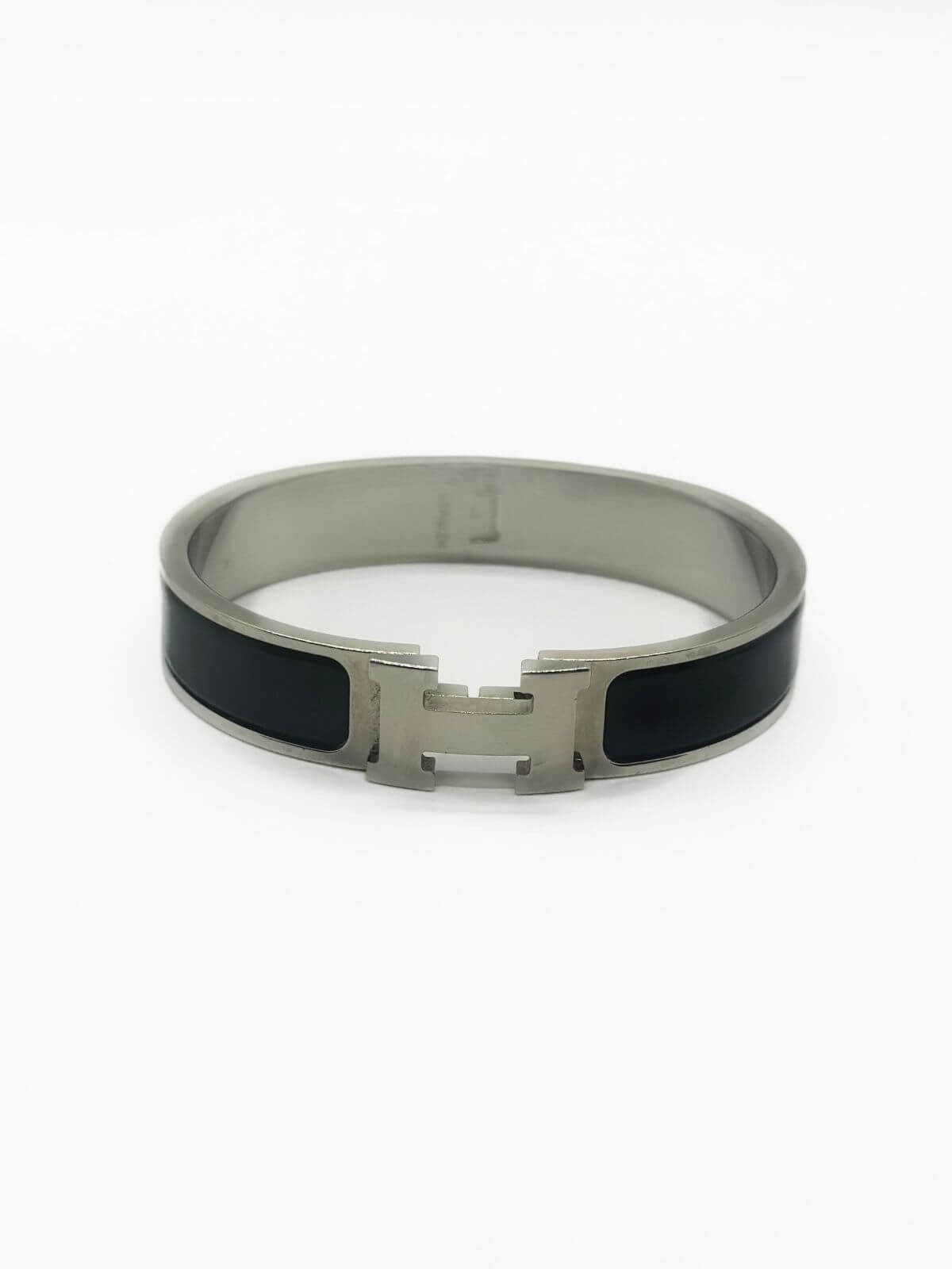 Hermes Clic H bracelet in stainless steel and black enamel on white background.