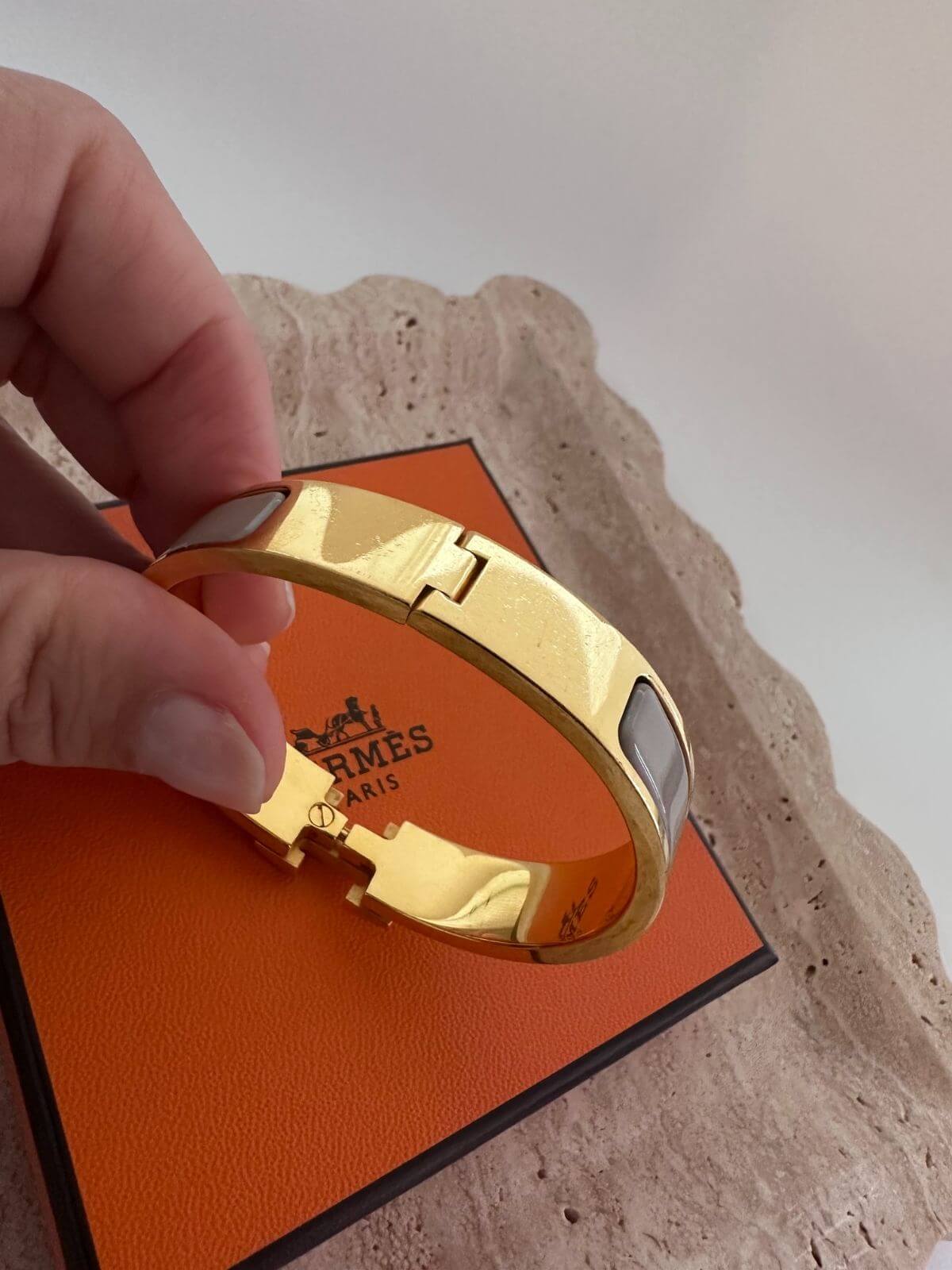 Back side of Hermes Clic H Bracelet with box on marble tray
