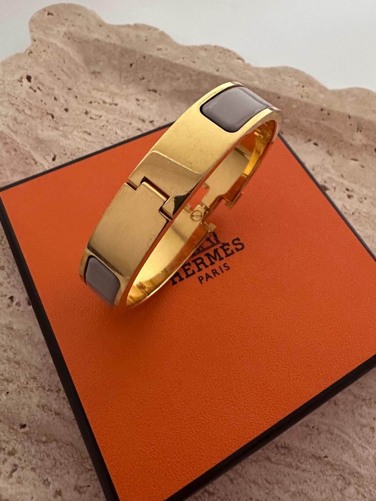 Back side of Hermes Clic H Bracelet with box on marble tray