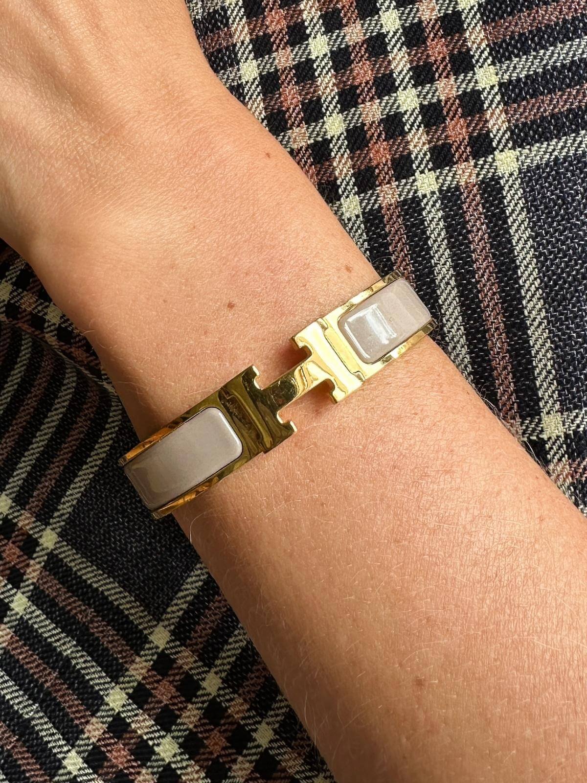 Model wearing Hermes Clic H Bracelet with plaid blazer, crop of just arm