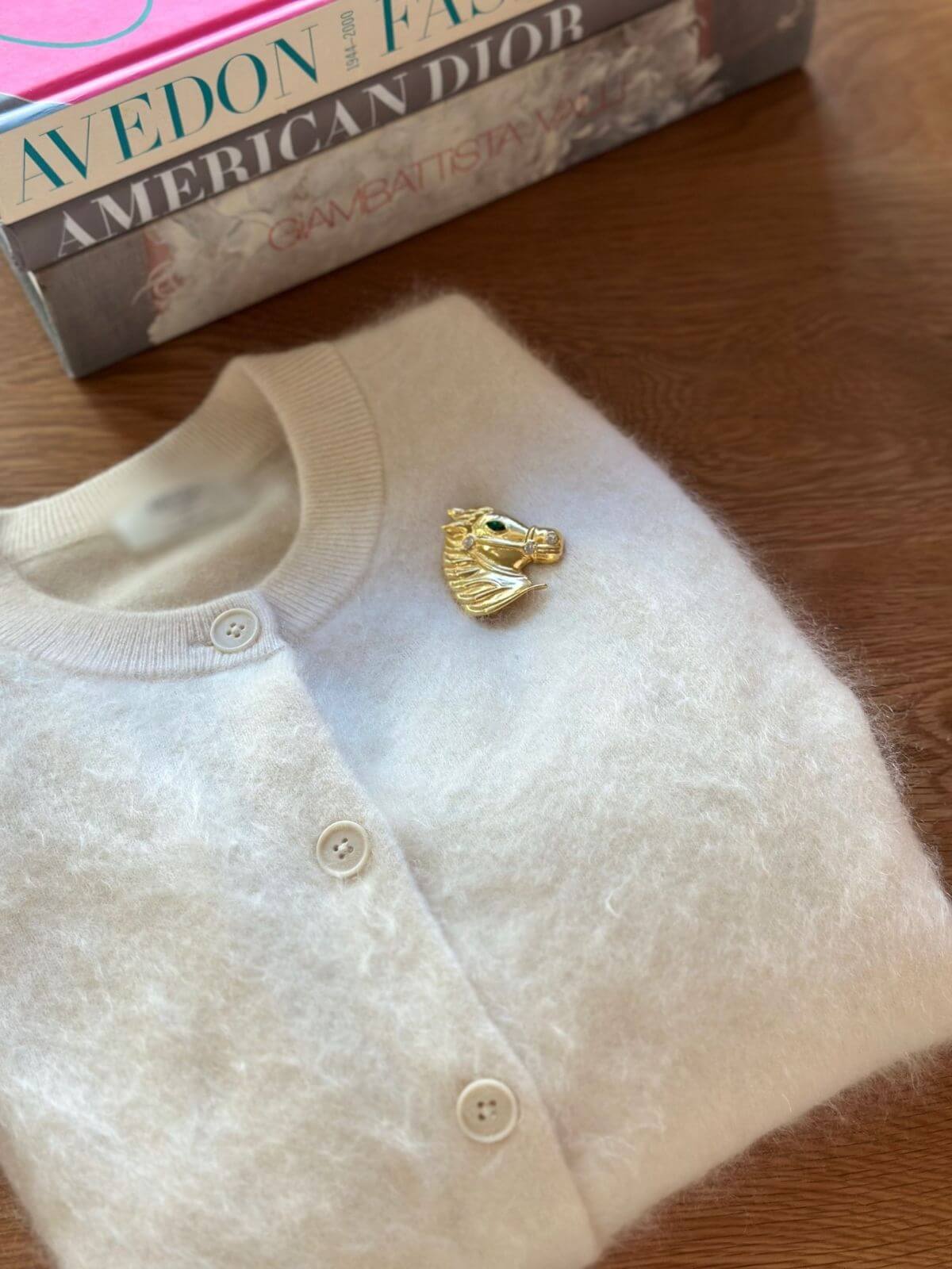 Louise Row Studio Vintage gold Horse Brooch on white cardigan on table