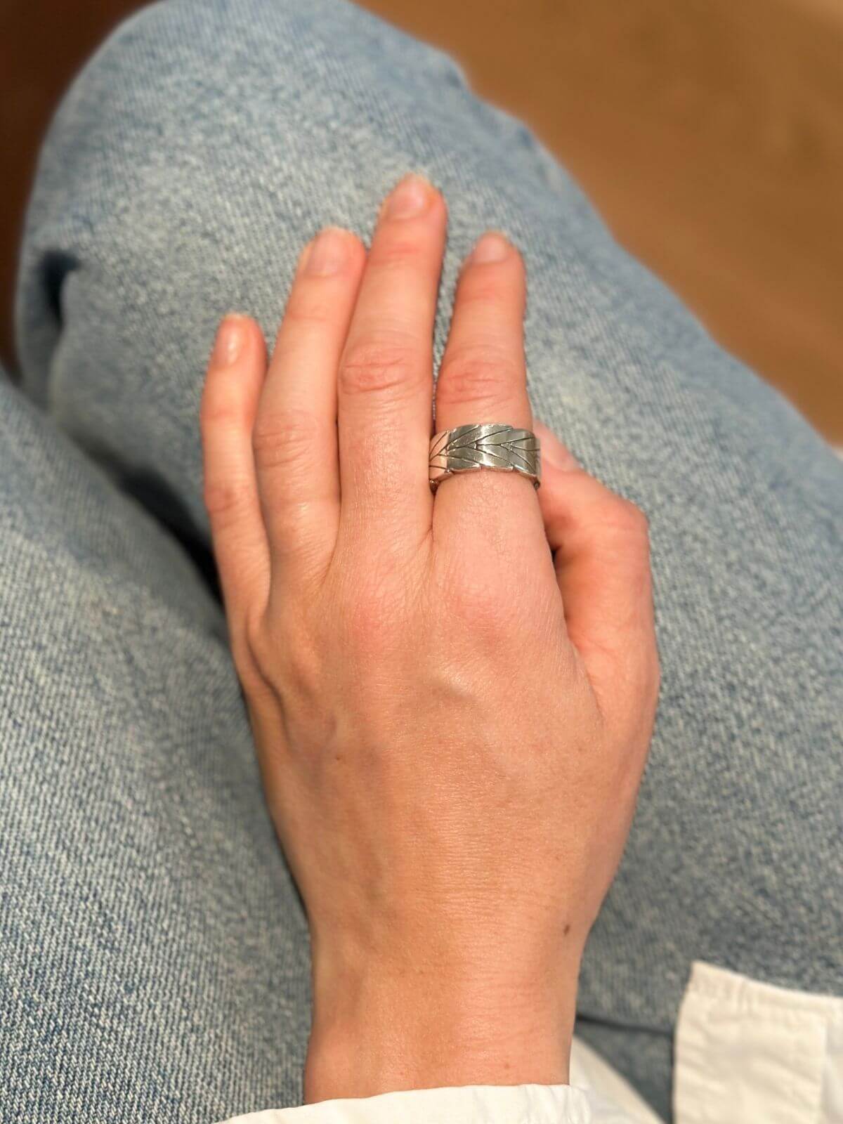 MOdel's hand wearing John Hardy Silver ring with chevron design.