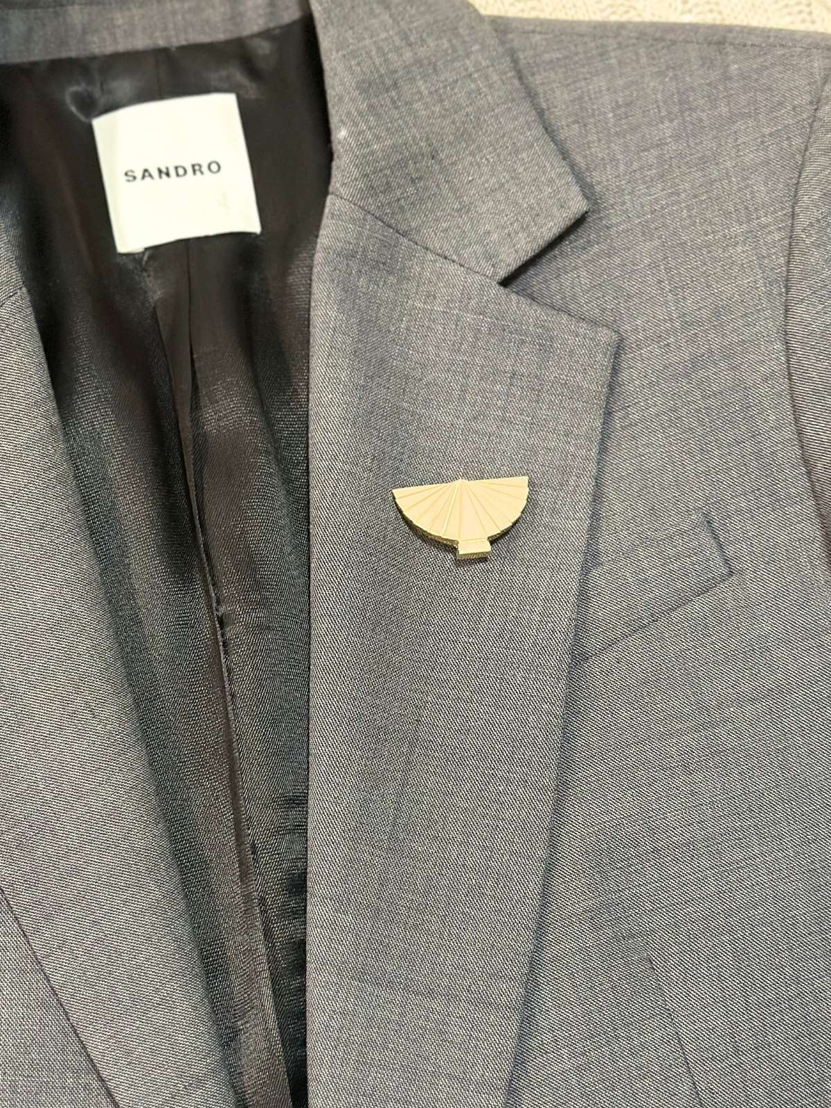 Louise Row Studio vintage Karl Lagerfeld gold fan brooch on a grey blazer