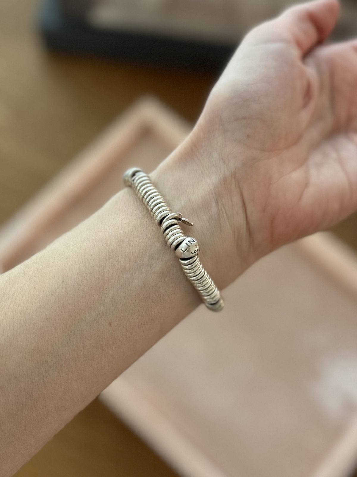 Silver Link of London Sweetie bracelet on pink background on arm