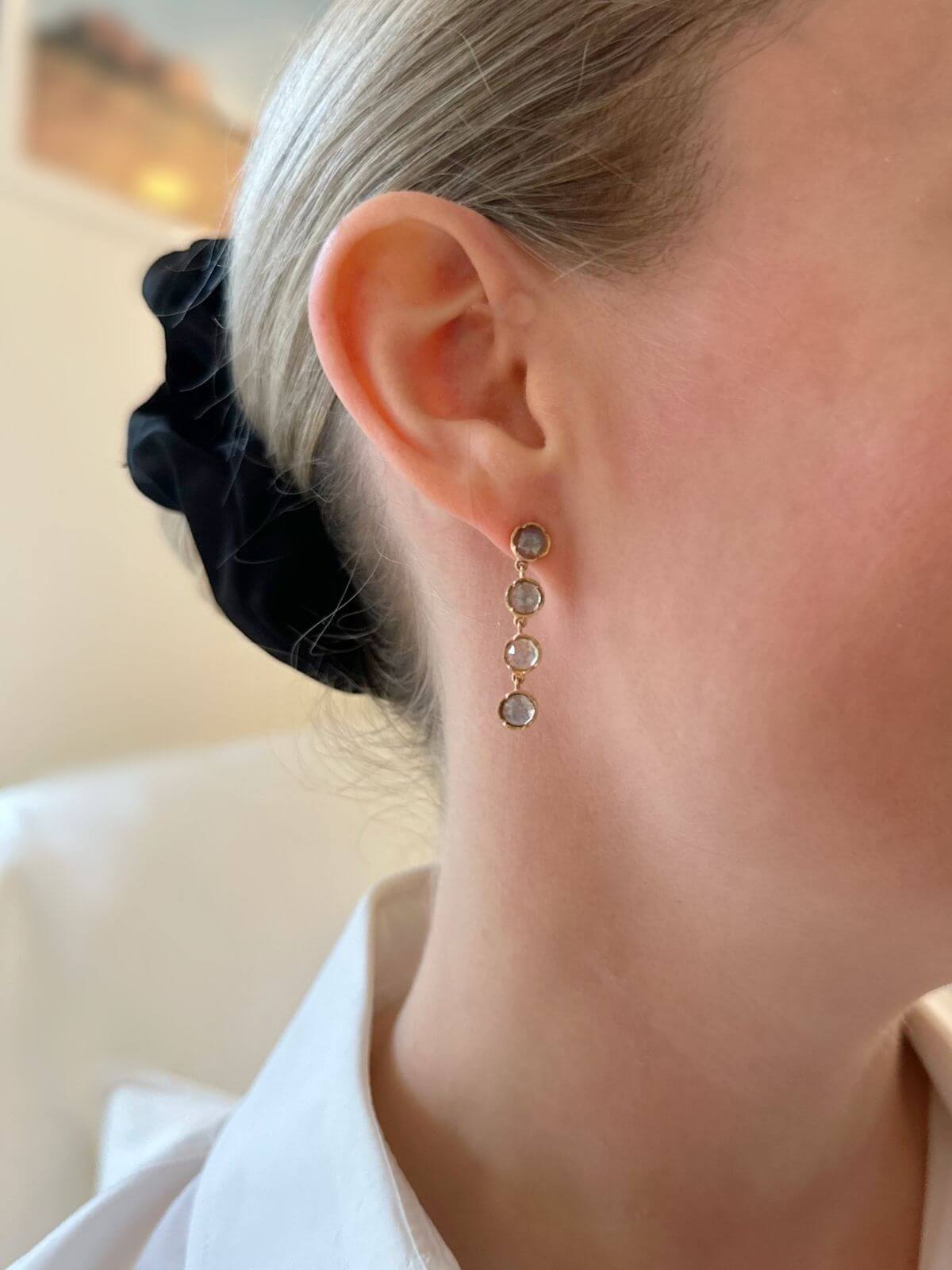 Close-up of an ear wearing a gold earring with multiple round stones.