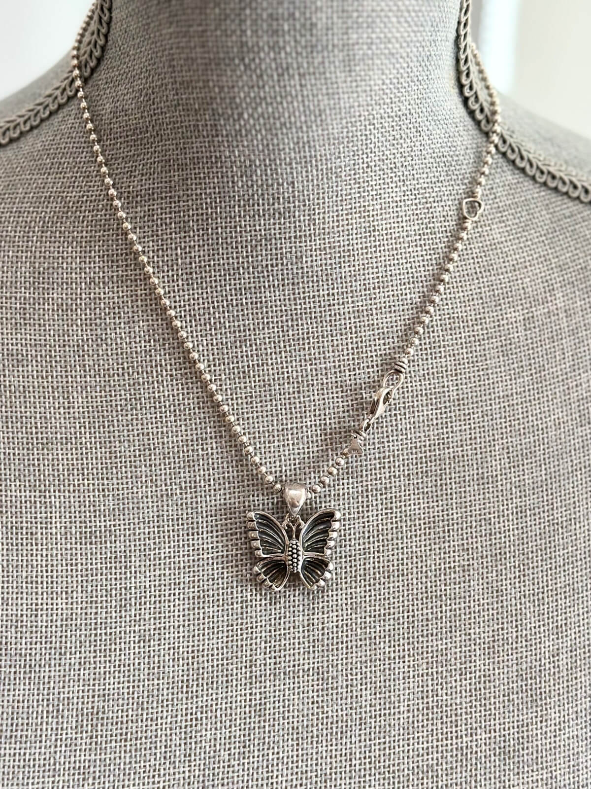 Louise Row featuring Lagos silver butterfly necklace on grey mannequin