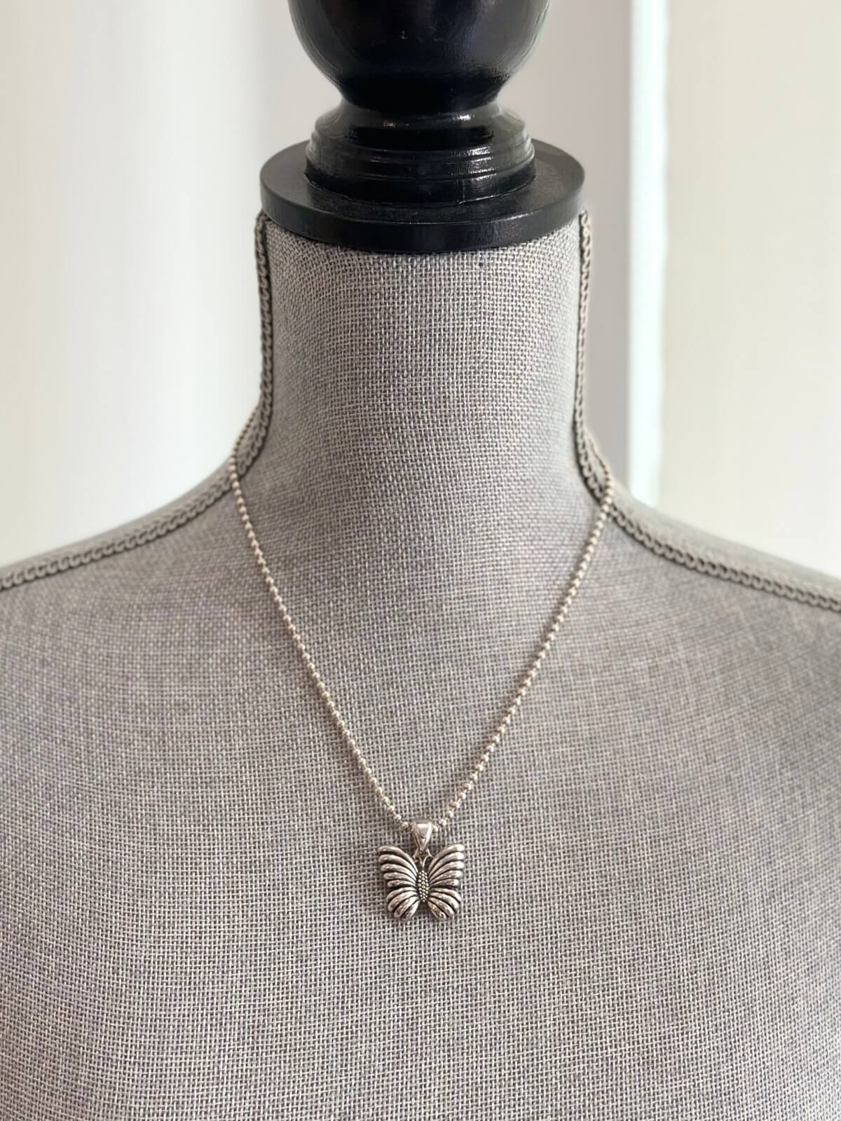 Louise Row featuring Lagos silver butterfly necklace on grey mannequin