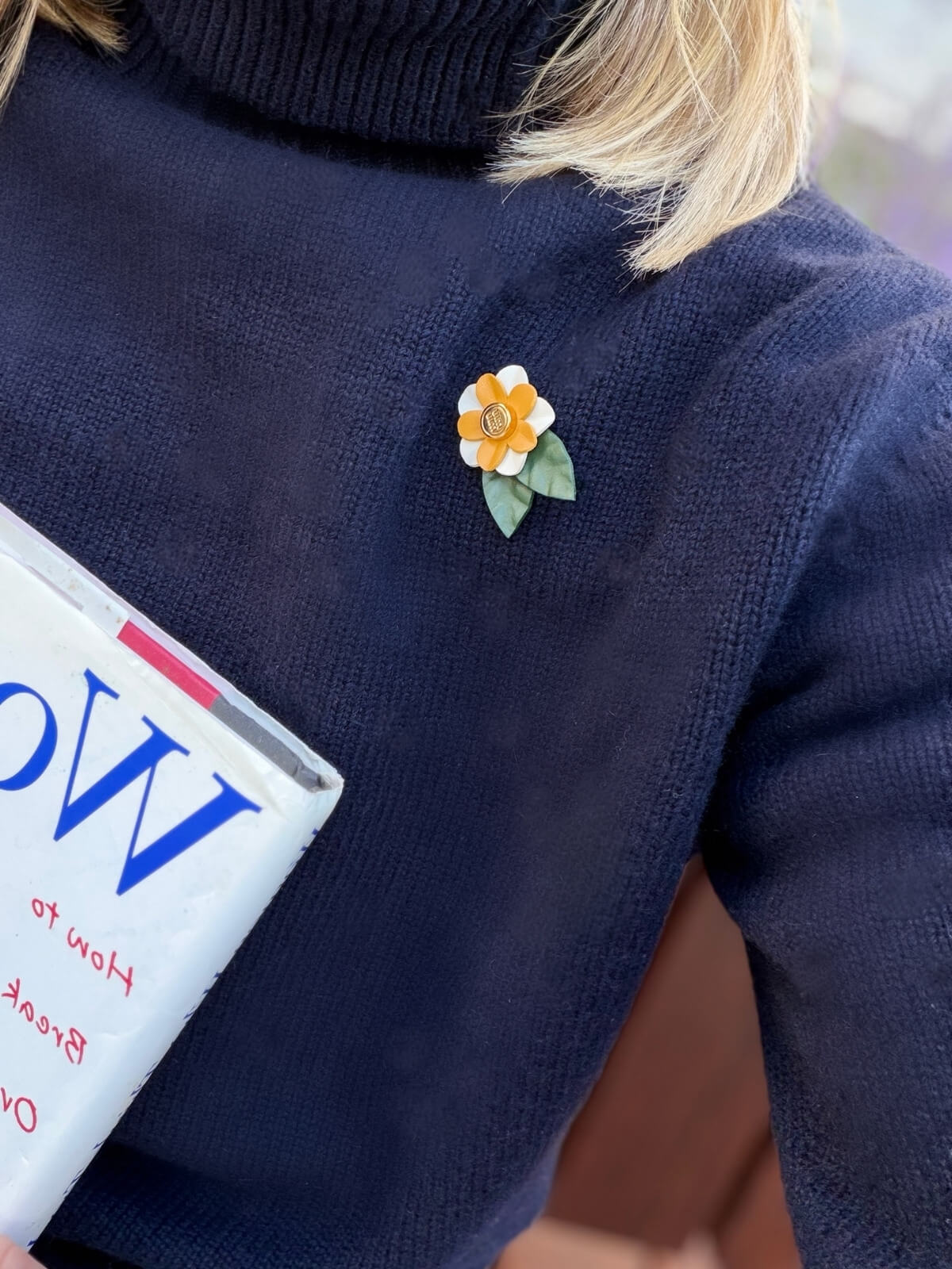 Louise Row featuring model in blue sweater wearing Miu Miu brooch.