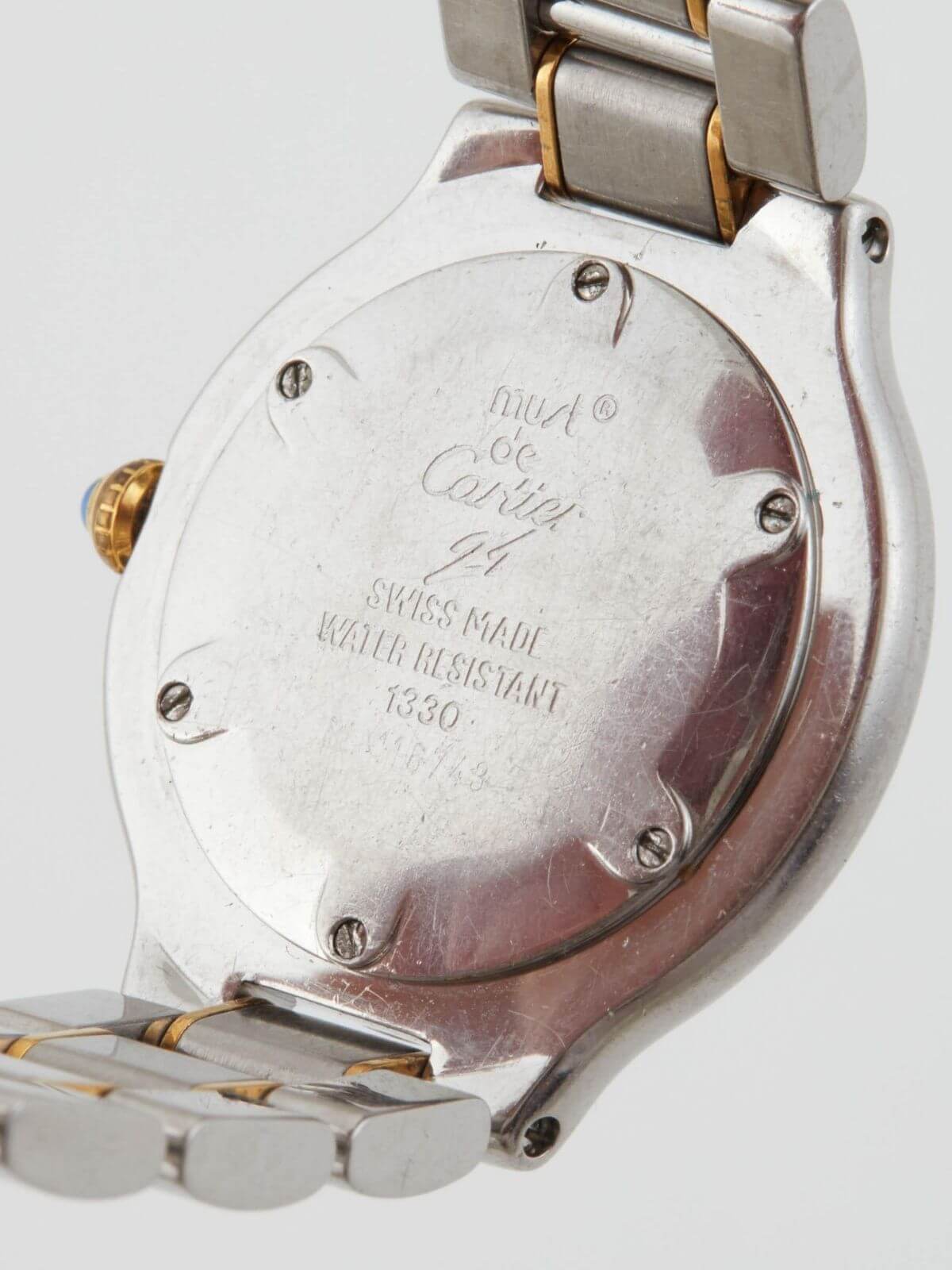 Back of watch Must De Cartier stainless steel and gold watch on white background. Round face .