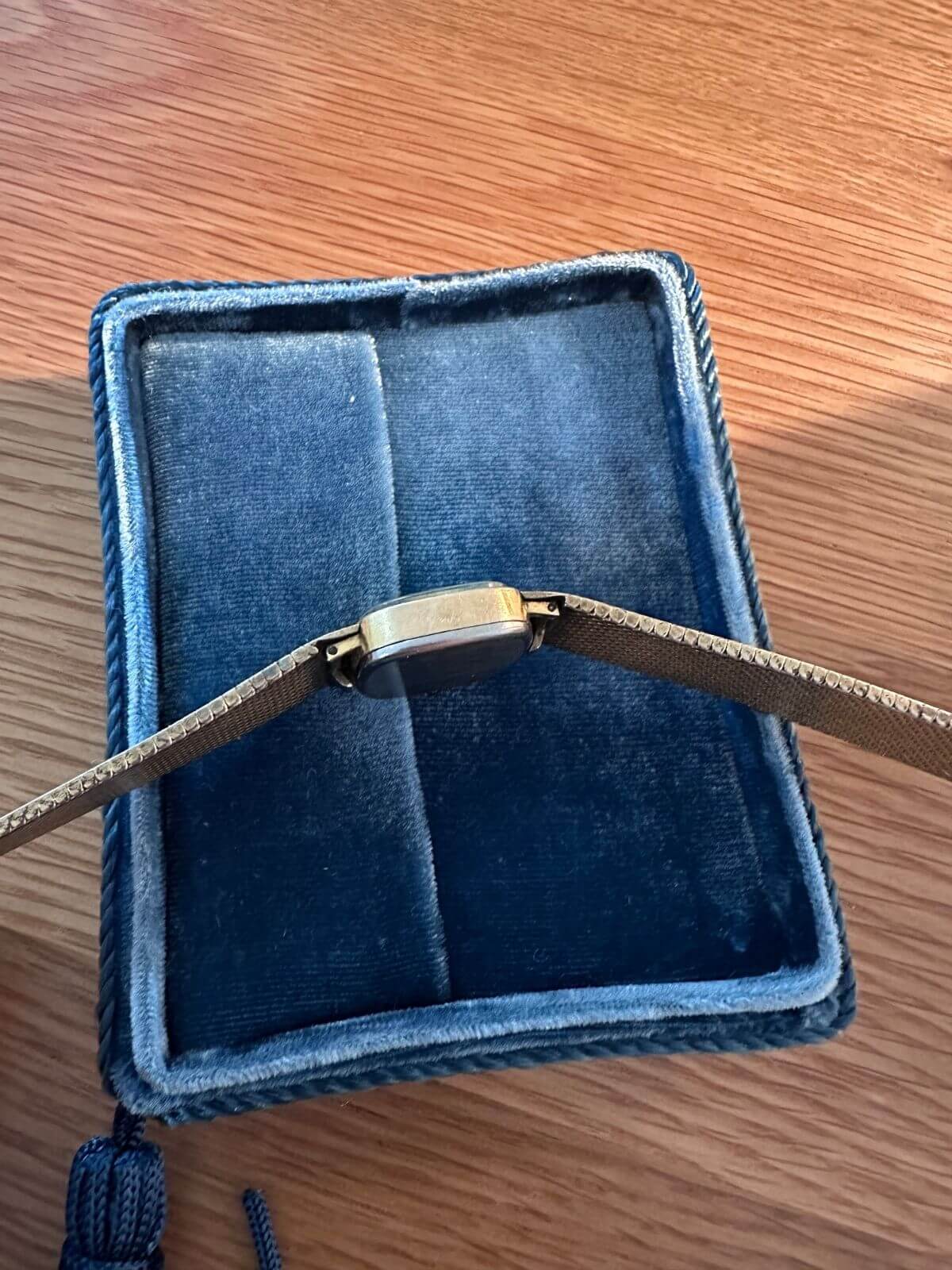 Louise Row Studio featuring Back of Gold Omega De Ville watch on wood table