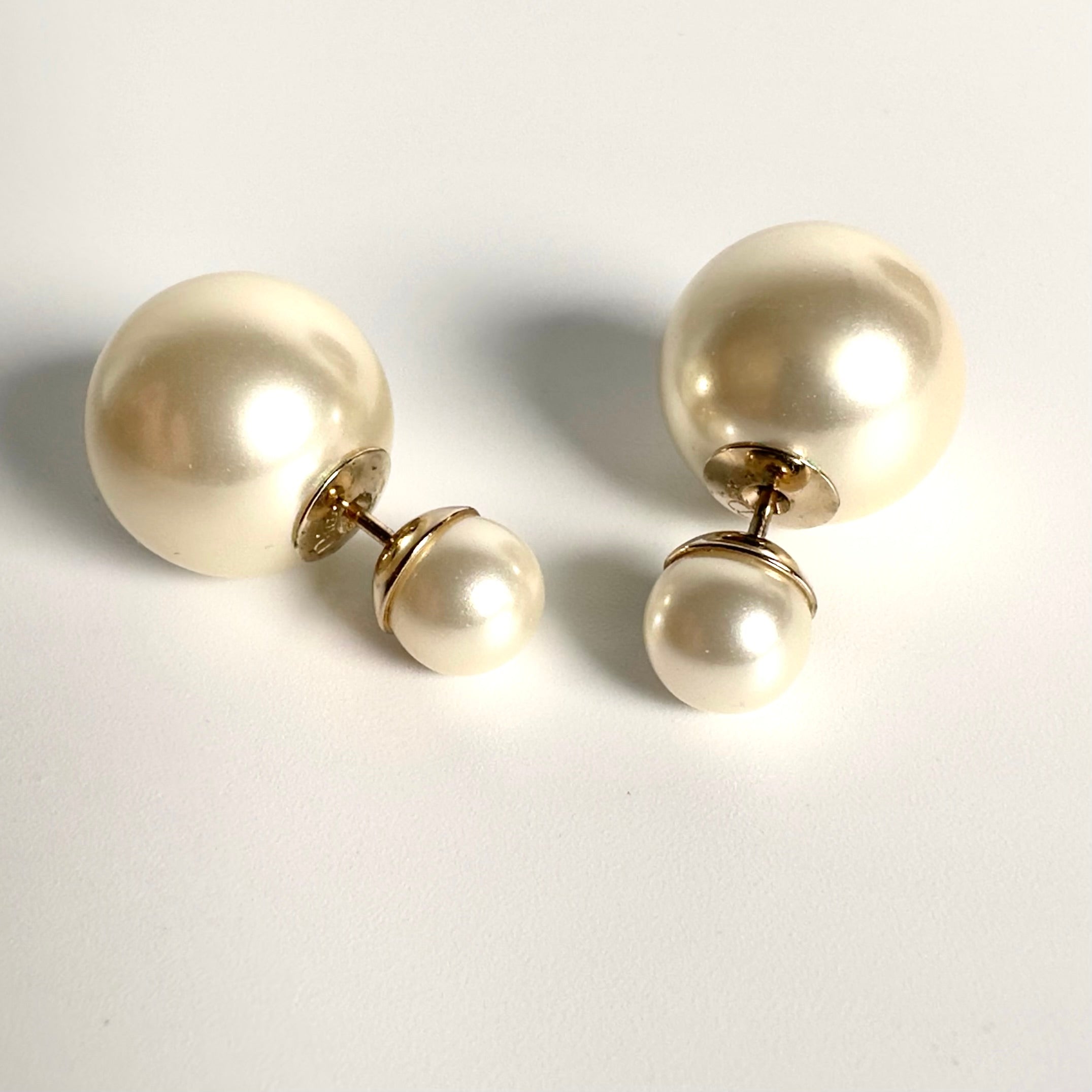 Pair of Dior pearl earrings on a light gray background