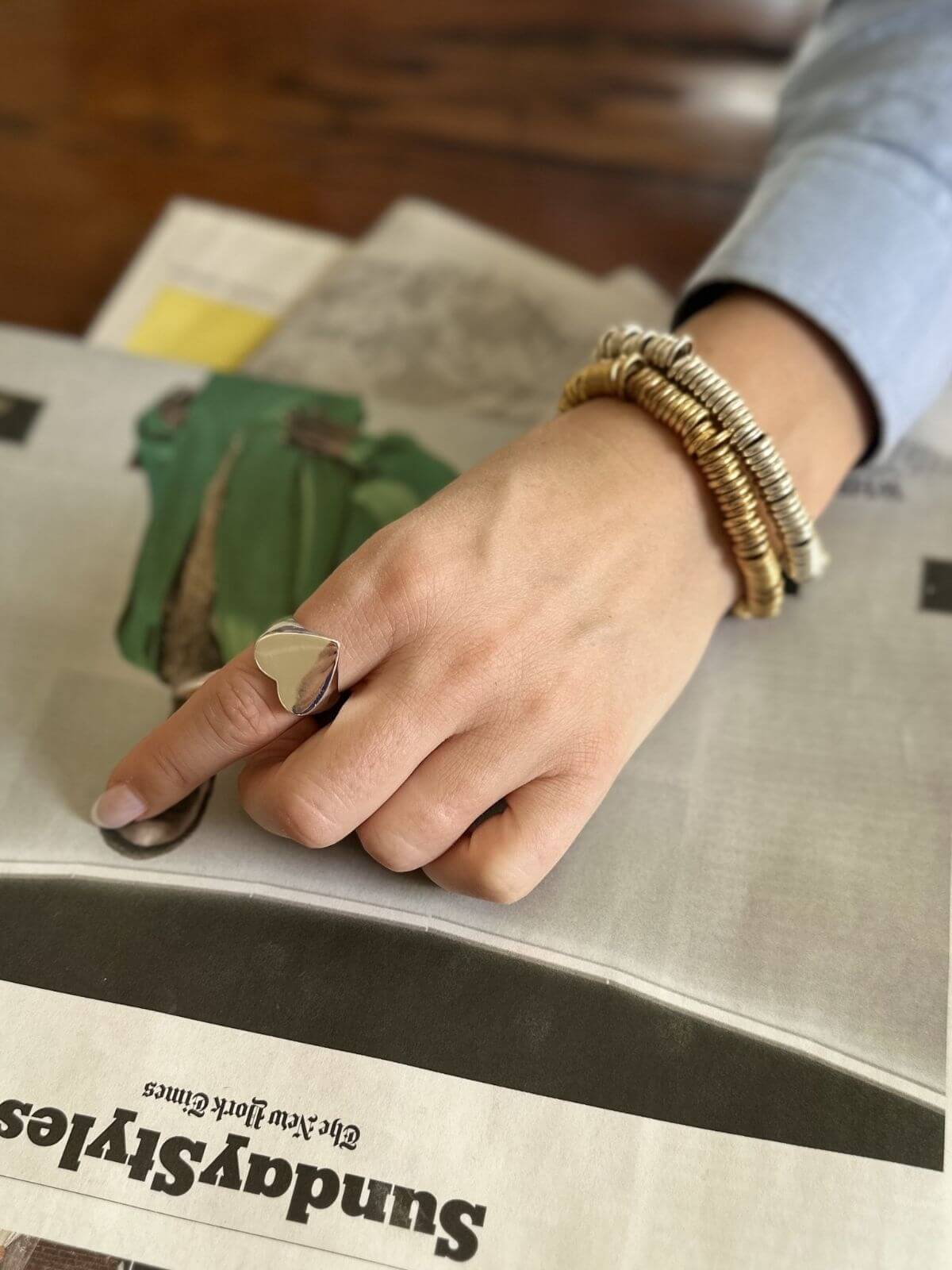 Hand with gold ring and bracelets on a newspaper background